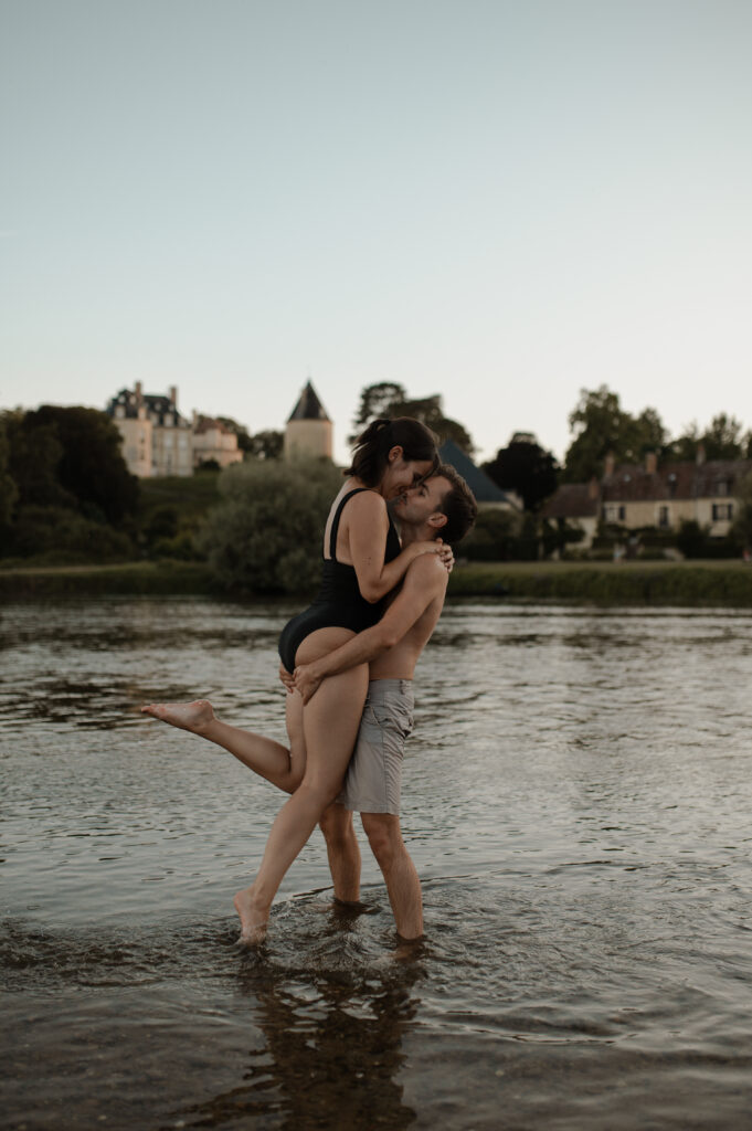 Couple s'embrassant dans l'eau, vue sur un château.