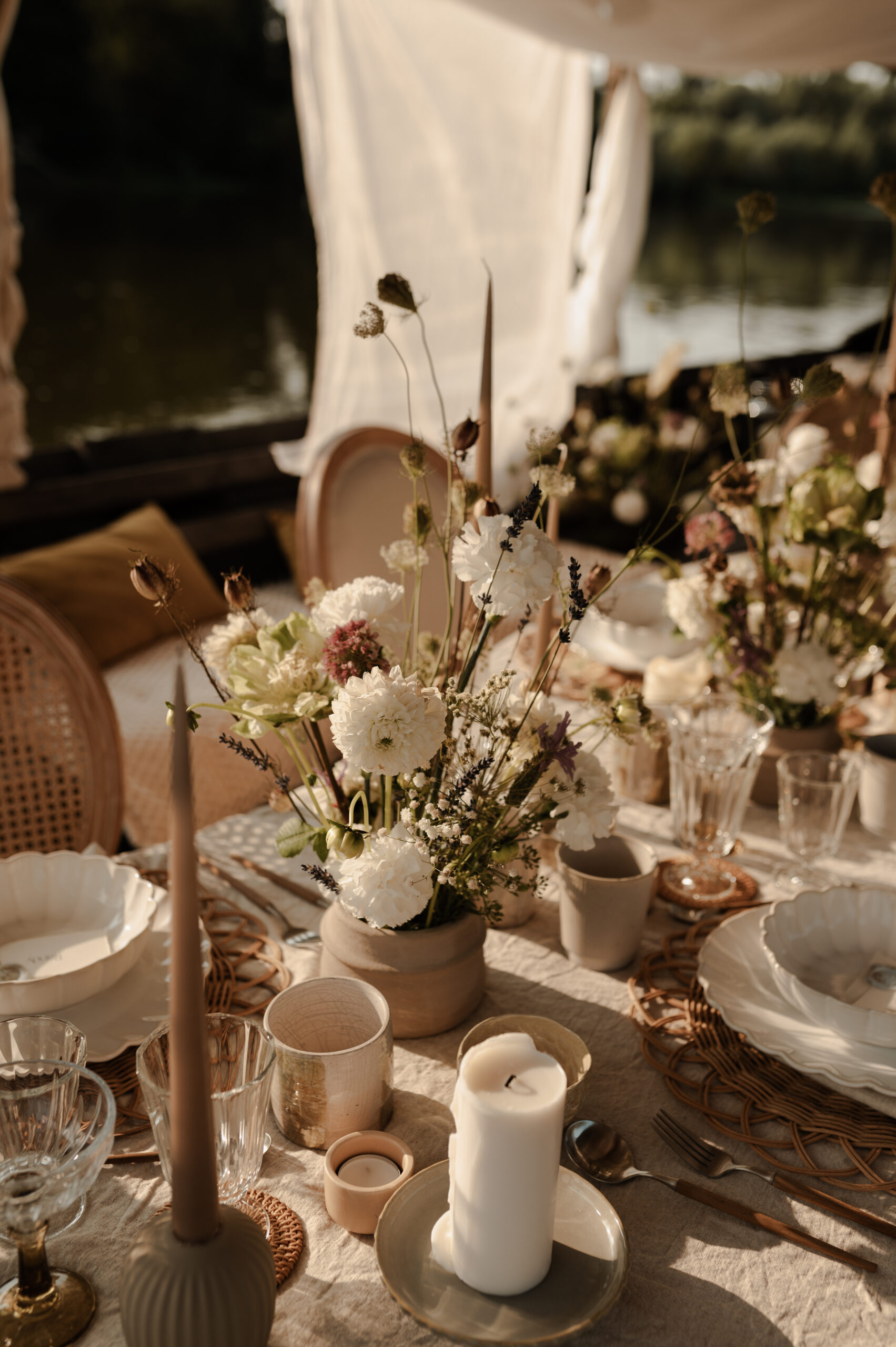 Flatlay détails table de mariage champêtre : fleurs séchées, bougies, vaisselle.