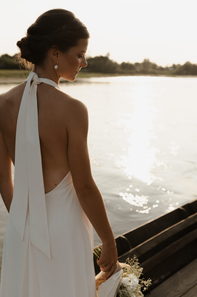 Photo dos de la mariée portant une robe dos nu blanche et coiffure relevée au coucher du soleil dans la Nièvre.