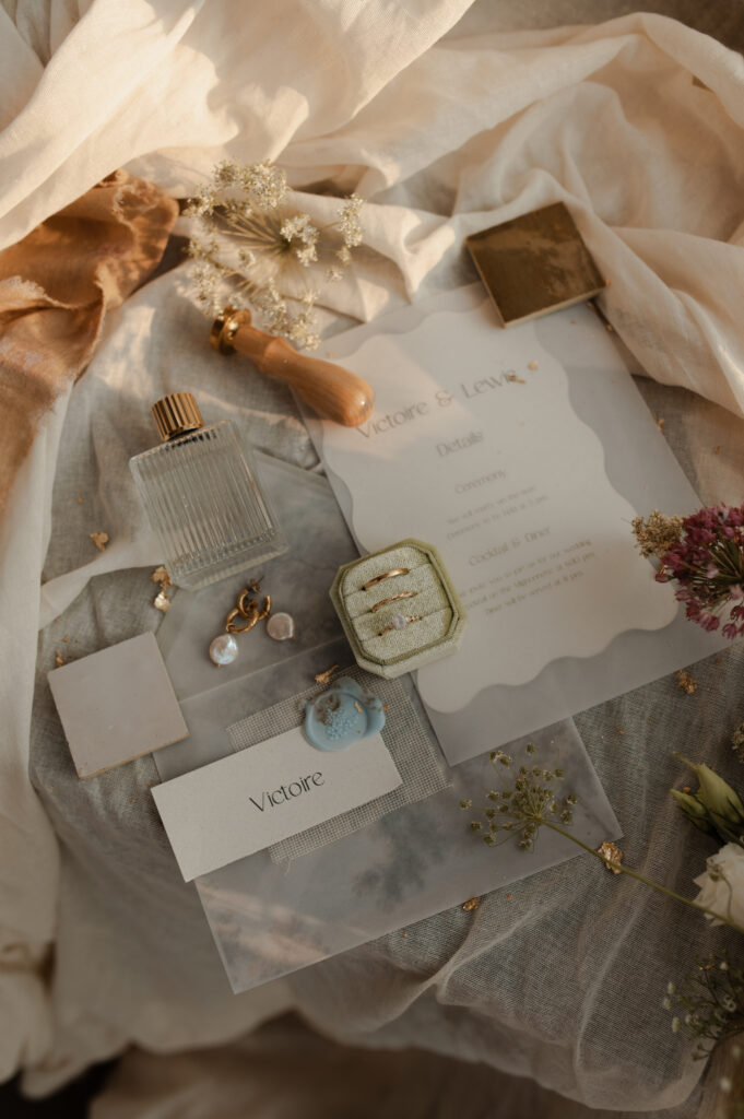 Flatlay détails préparatifs de la mariée dans la Nièvre : alliance, papeterie, cachet de cire.