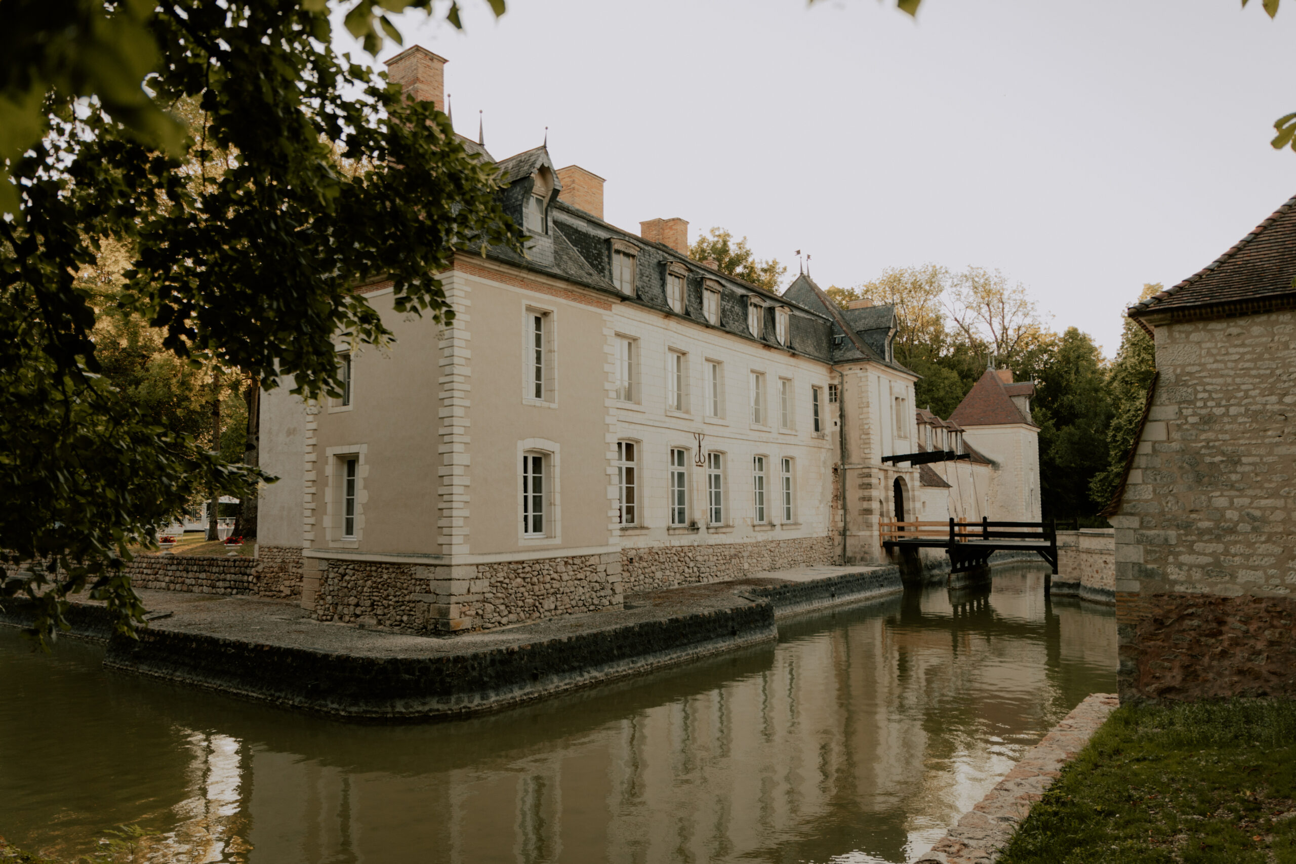 Vue latérale du Château de Droupt-Saint-Basle avec les douves et un arbre encadrant la façade.
