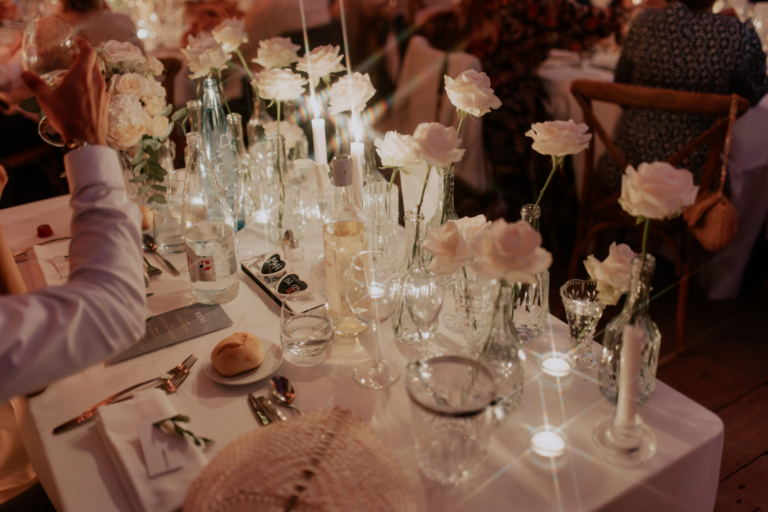 Décoration de table de mariage chic et élégante en Dordogne avec roses blanches et bougies. Gros plan floral haut de gamme.