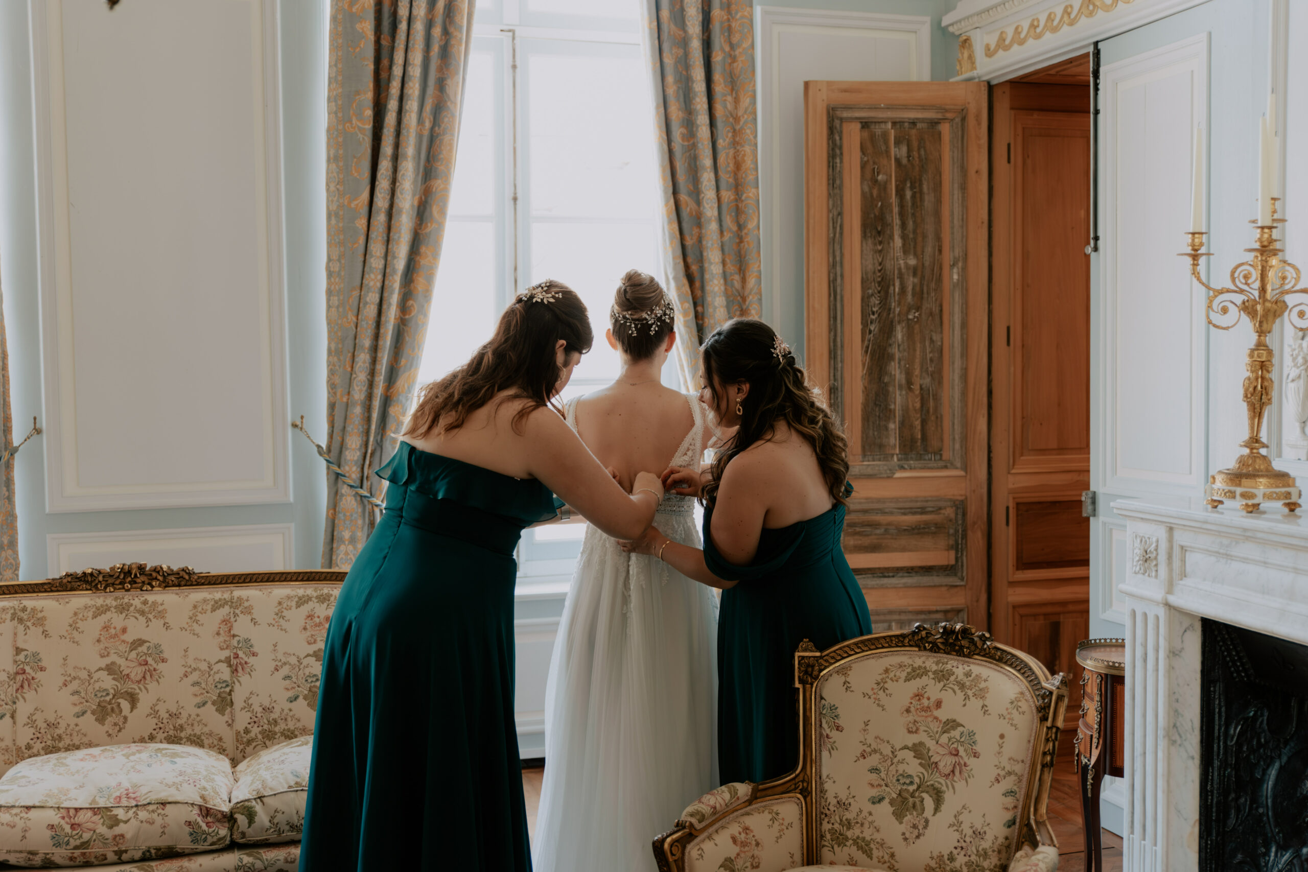 Témoins fermant la robe de la mariée dans le salon bleu du Château de Droupt-Saint-Basle.