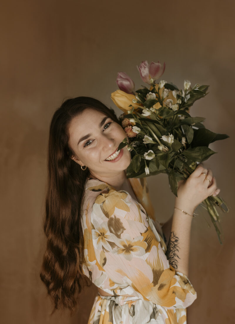 Portrait de la photographe de mariage professionnelle pour le Champagne, la Nièvre et la Dordogne, souriante et tenant un bouquet de fleurs. Photographe édito Champagne-Ardenne, Périgord, Nevers.