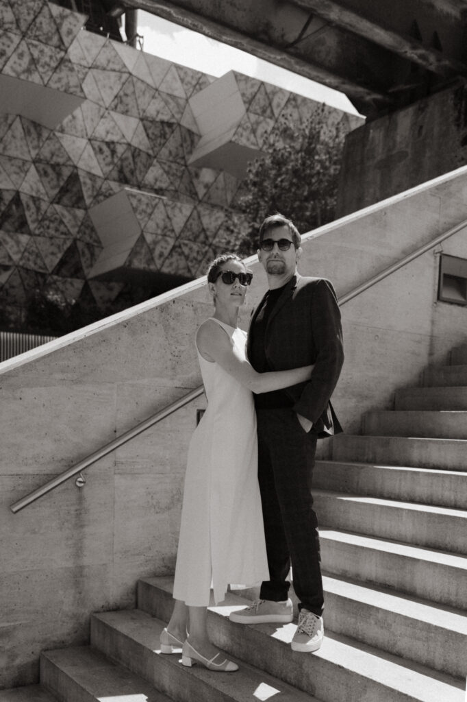 Couple de mariés en tenue moderne posant sur un escalier à Sarlat.