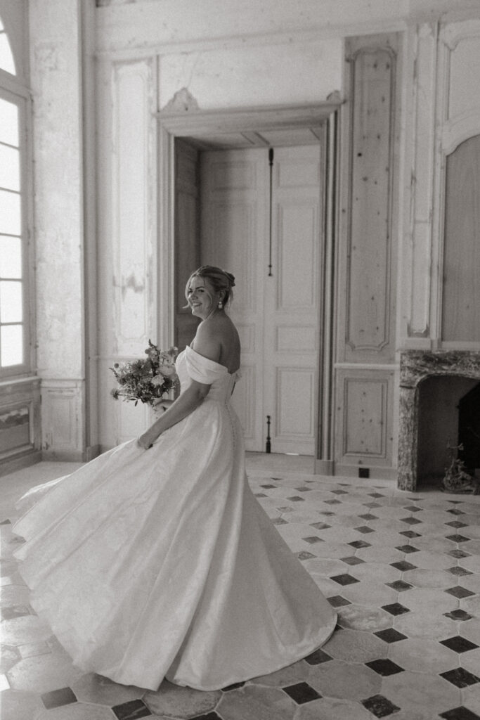 Mariée tournant dans sa robe blanche dans une salle historique élégante au Château de Vaux en Champagne.