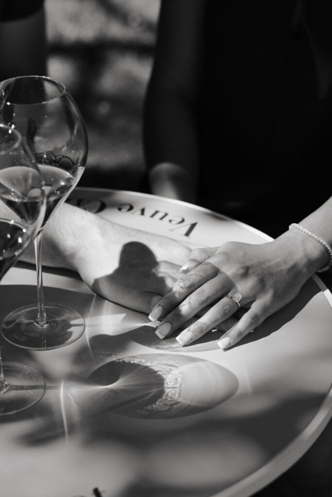 Photo en noir et blanc d'une alliance sur une table Veuve Clicquot.