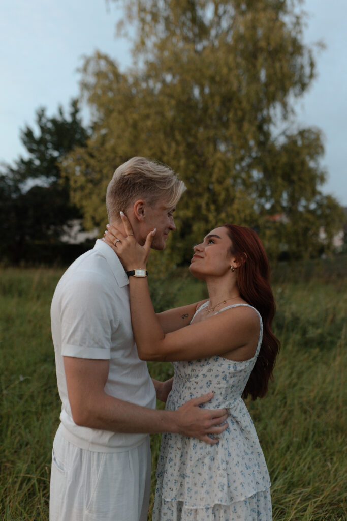Portrait intime en couleur d'un couple s'embrassant sur le front. Ils se regardent profondément dans les yeux, lors d'une séance photo douce et lumineuse près de Reims, Champagne-Ardenne.