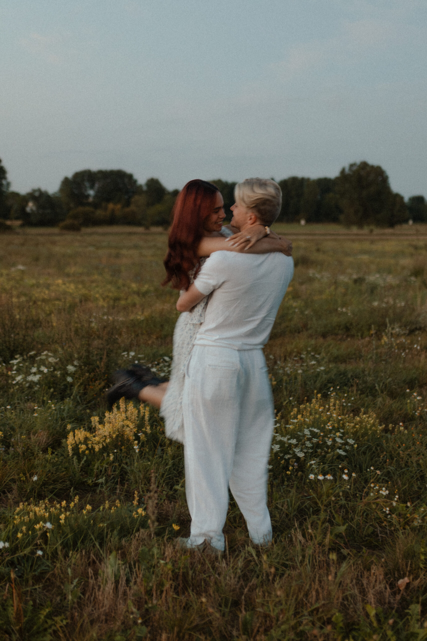 Photographie en couleur d'un couple lors d'une séance photo à la Blue Hour près de Reims, Champagne-Ardenne. L'homme porte sa femme, ils se regardent profondément, avec un flou de mouvement capturant le dynamisme.