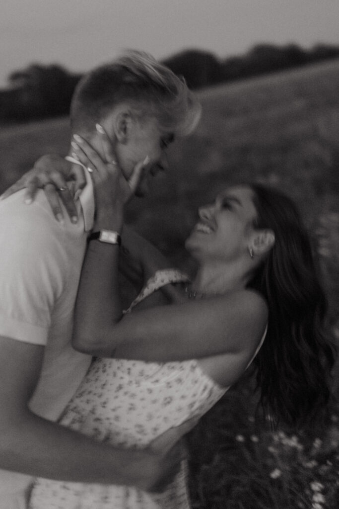 Photographie en noir et blanc d'un couple en flou de mouvement. Ils se balancent et se regardent droit dans les yeux, tout en ayant un magnifique sourire.