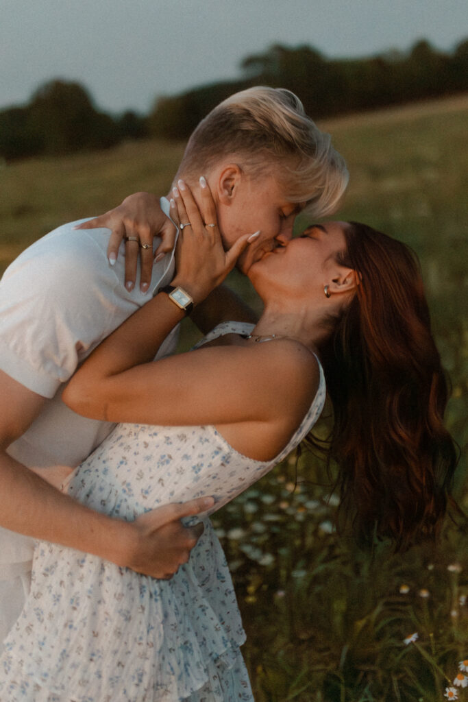 Photographie en couleur d'un couple lors d'une séance photo à la Golden Hour près de Reims, Champagne-Ardenne. L'homme soutient sa femme dans une pose balancée pour un baiser passionné (deep kiss), avec un flou de mouvement capturant le dynamisme.