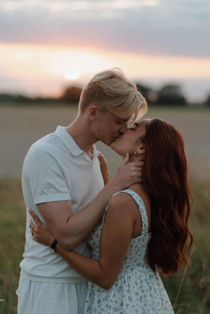 Portrait très rapproché en couleur lors d'une séance engagement à Prunay, près de Reims, au coucher du soleil. Les visages d'un couple se font face, ils s'embrassent passionnément, entourés de hautes herbes dorées.
