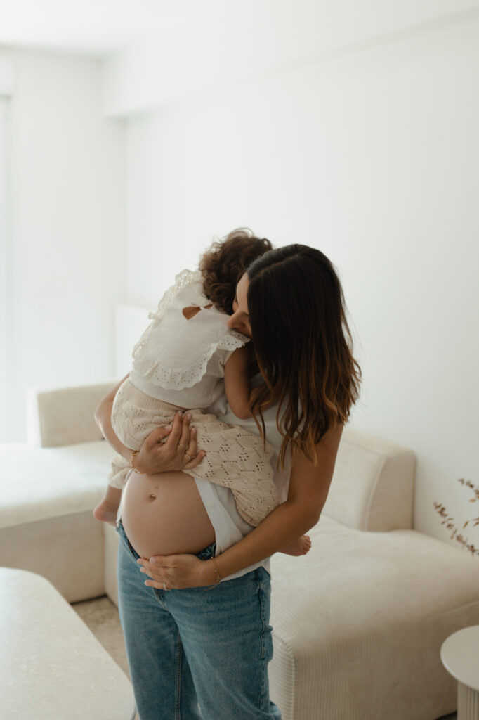Femme enceinte portant un bébé dans ses bras, séance photo famille et grossesse à Reims.