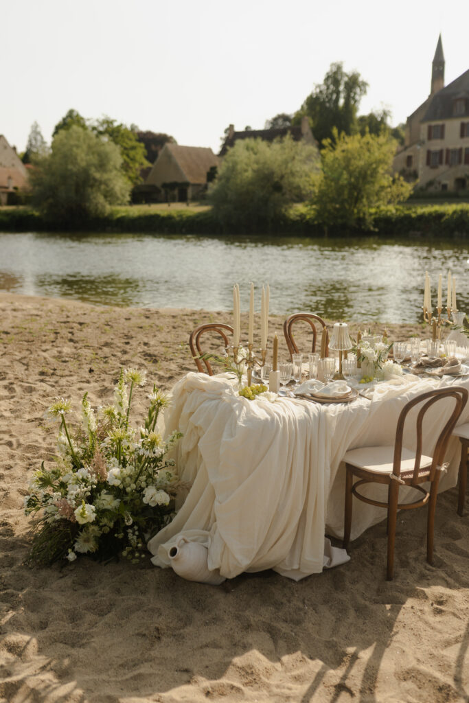 Table de mariage décorée en extérieur sur une plage de rivière en Dordogne.