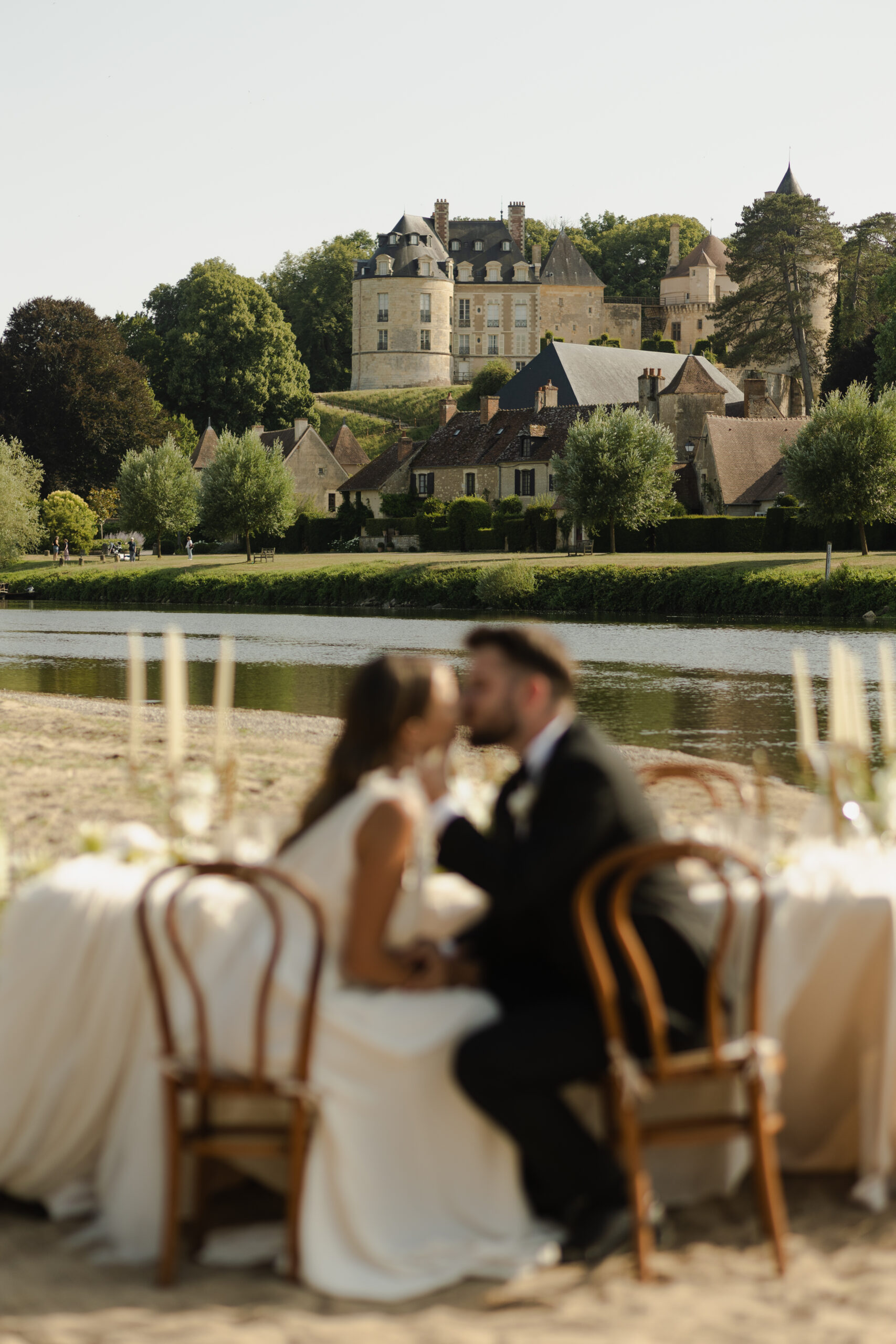 Mariés assis à une table de banquet face à un château médiéval en Bourgogne-Franche-Comté.
