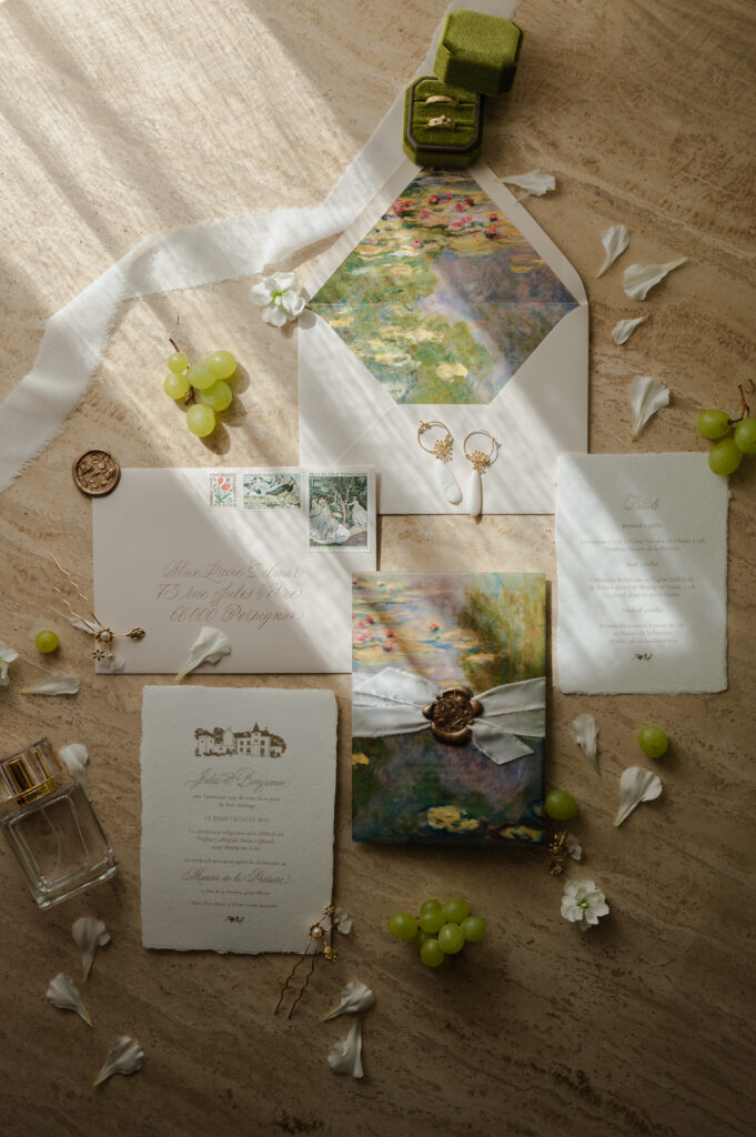 Flatlay détaillé d'une invitation de mariage, à Sarlat en Dordogne, élégante avec cachet de cire et raisins de Champagne.