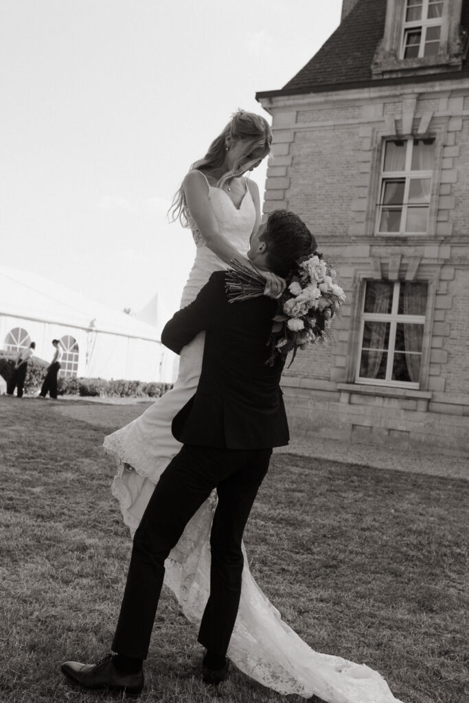 Marié portant sa femme devant un château historique lors d'un mariage dans la Nièvre.
