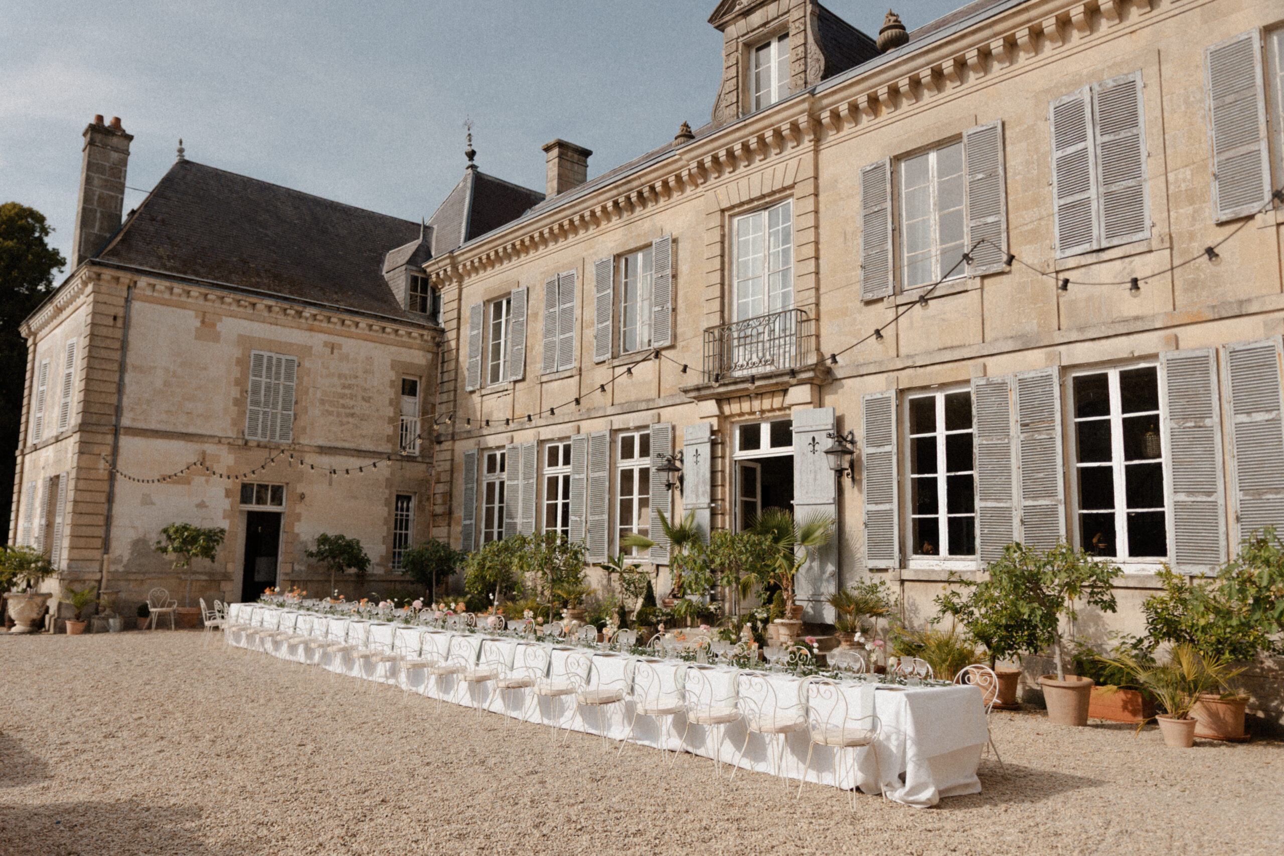 Vue de côté d'une table de banquet devant la façade du Château de Mairy sous une lumière douce.