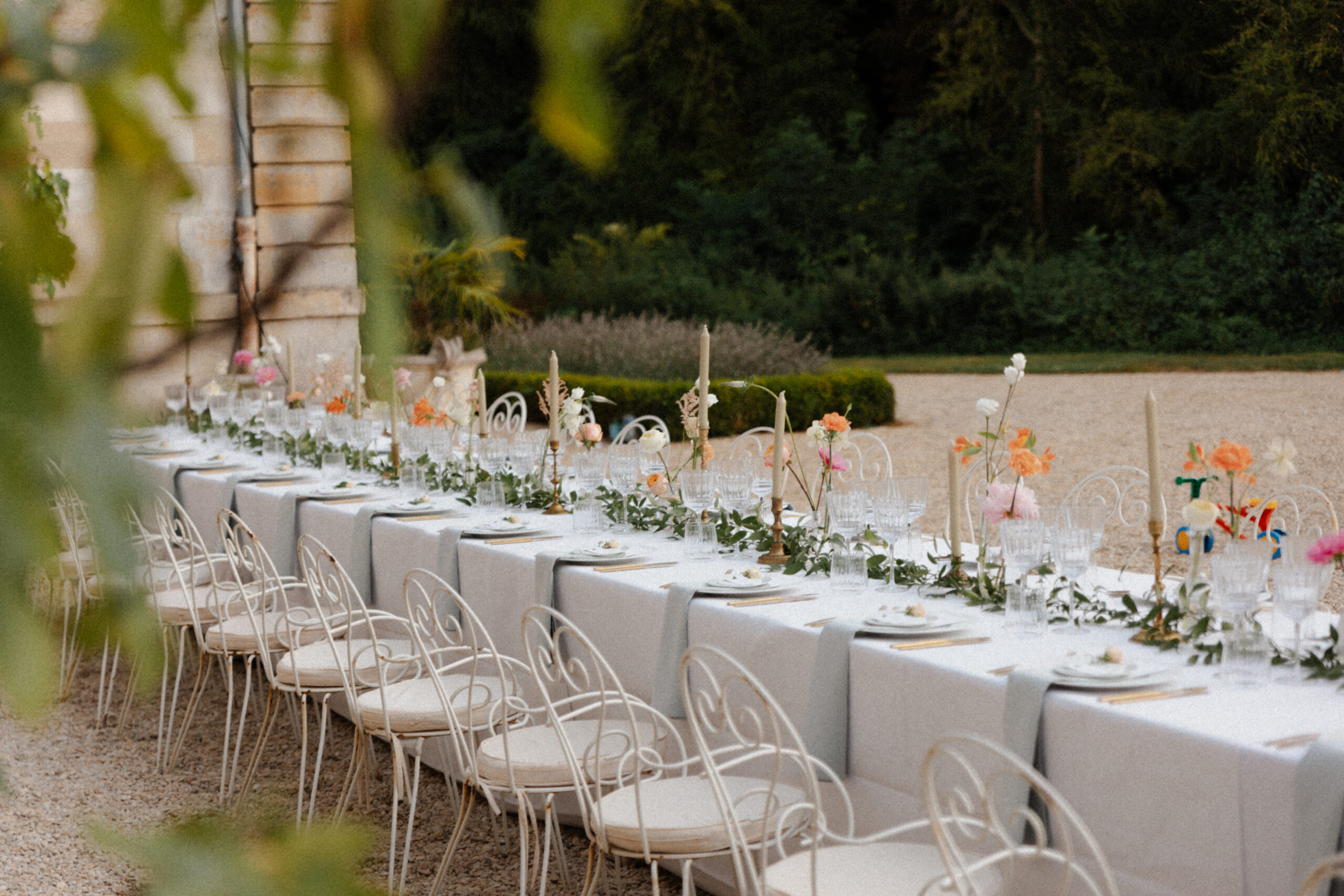 Table de banquet de mariage à Mairy photographiée en immersion derrière une plante du parc.