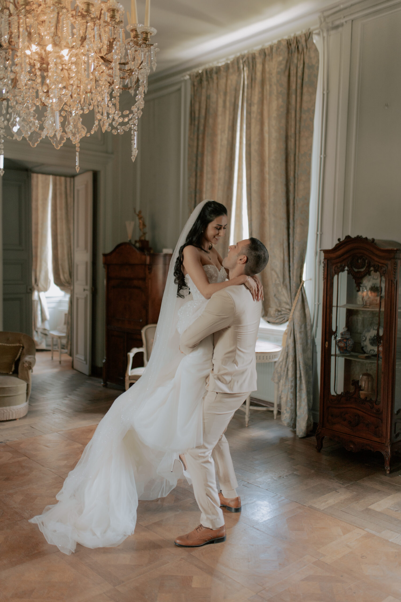 Mariés s'enlaçant dans le salon du Château de Mairy. Le marié fait tournoyer sa femme amoureusement.