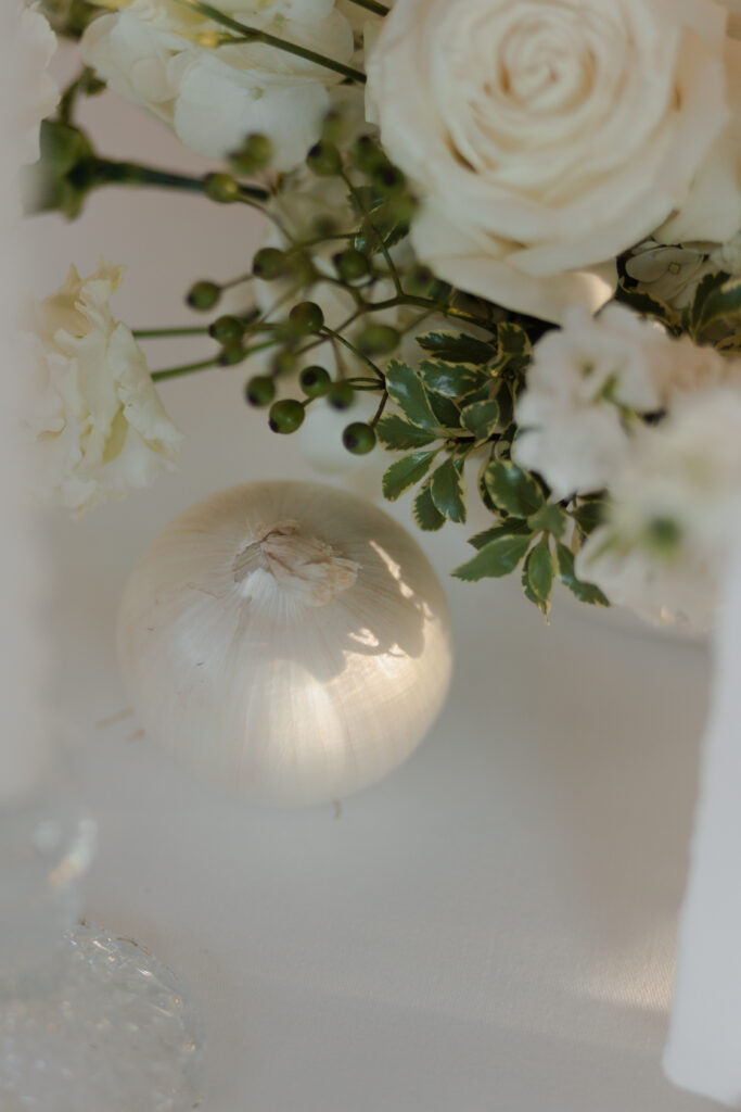 Gros plan sur un oignon intégré dans un centre de table floral sophistiqué.