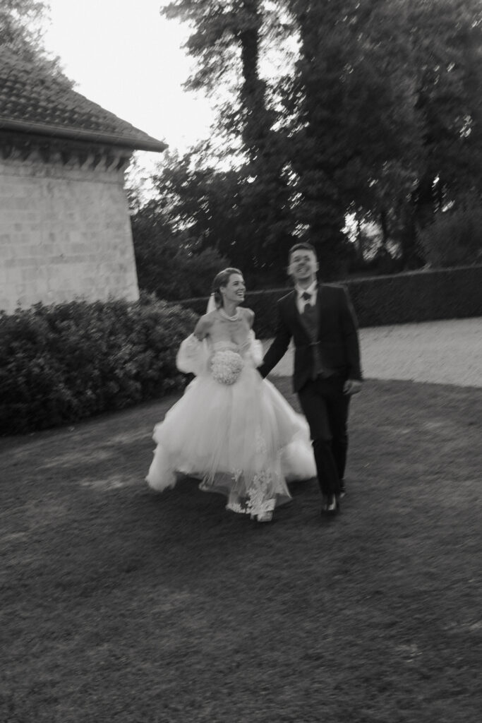 Photo de couple noir et blanc, avec un flou de mouvement. Les mariés courent vers la photographe pendant un mariage au Domaine de Vaugency.