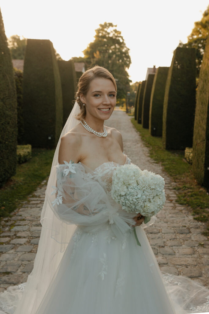 Portrait de la mariée style éditorial, portant un bouquet d'hortensias au Domaine de Vaugency.