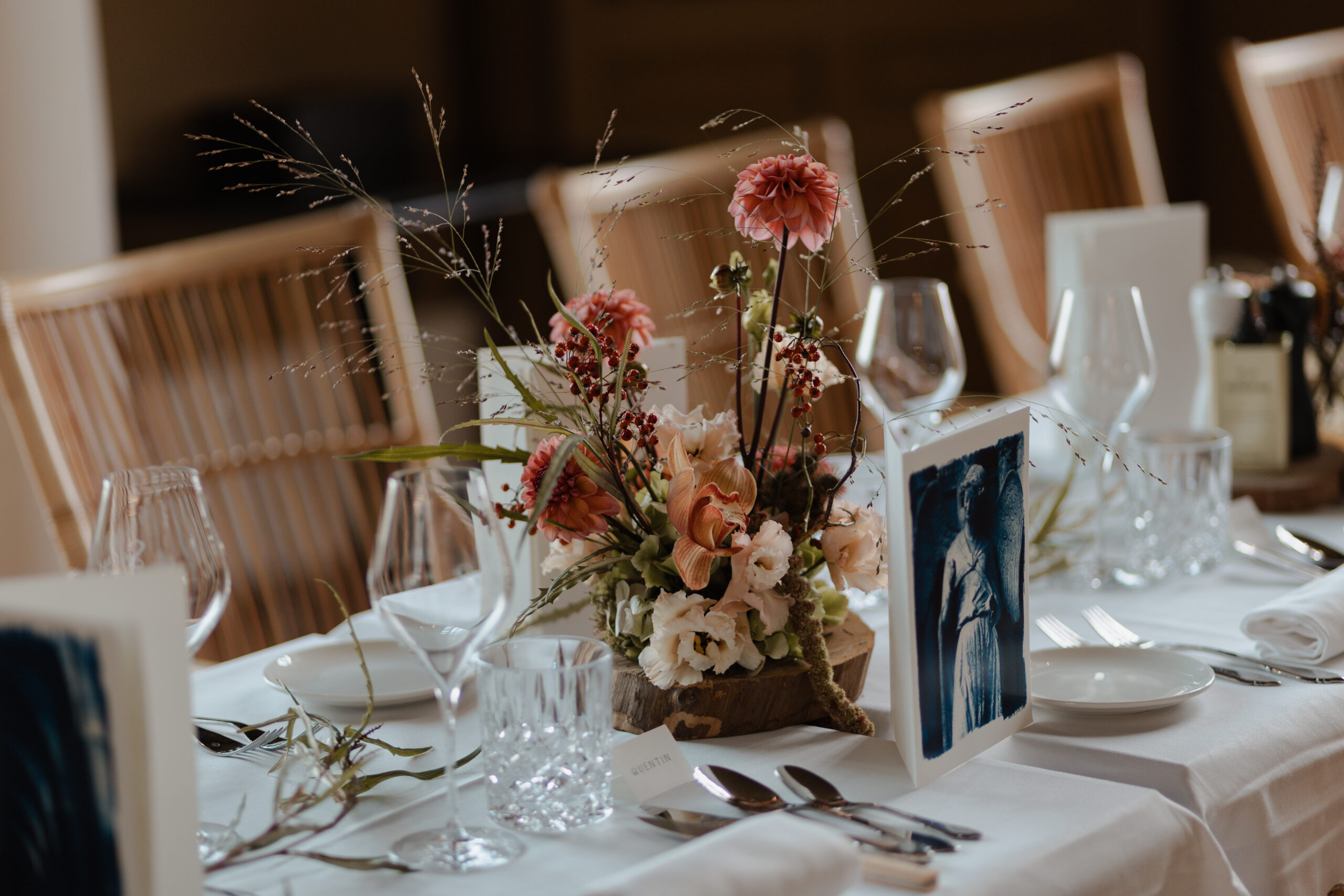 Gros plan sur une composition florale de mariage et un menu personnalisés sur une table du Château de Sacy. Focus sur les textures et les détails raffinés.