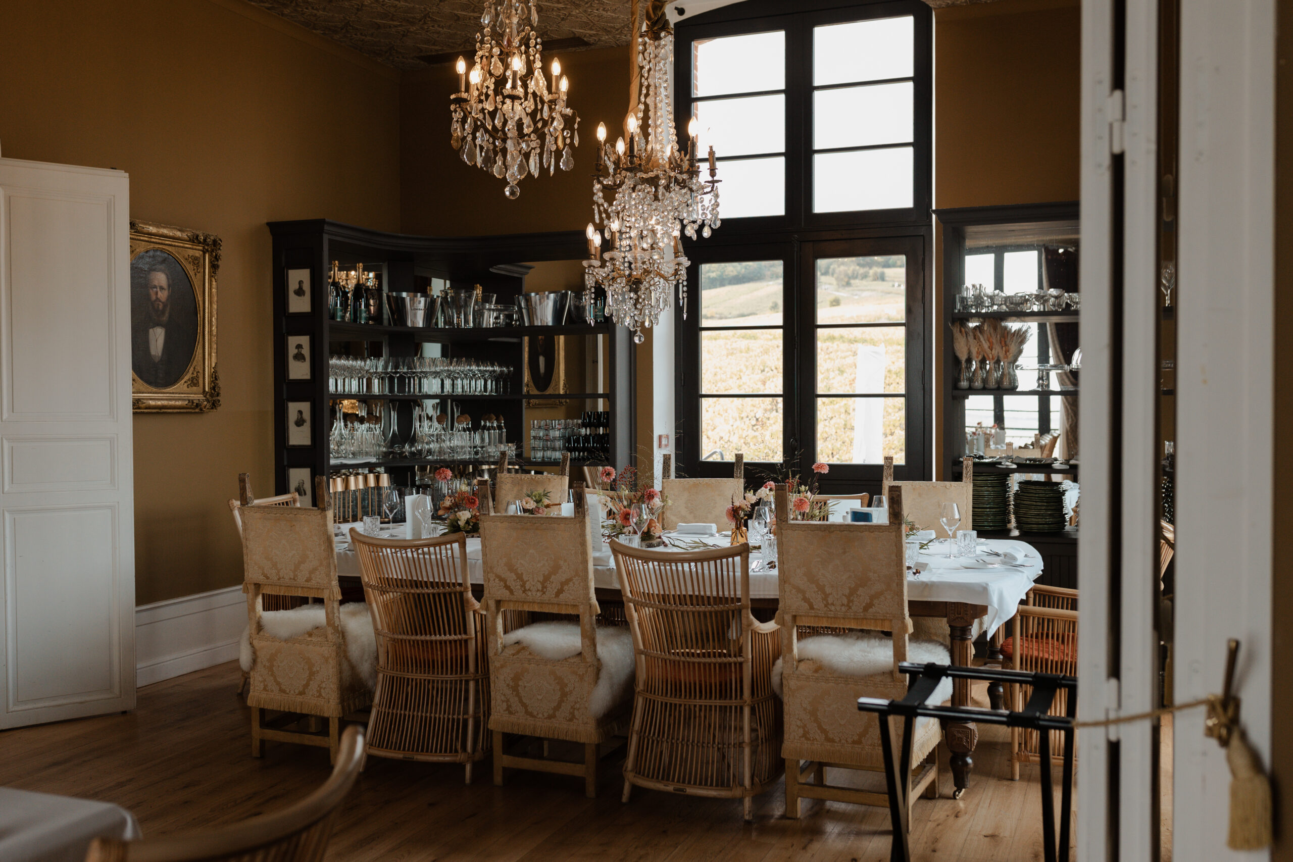 Salle de réception du Château de Sacy mettant en valeur deux magnifiques lustres luxueux surplombant une table de mariage dressée.