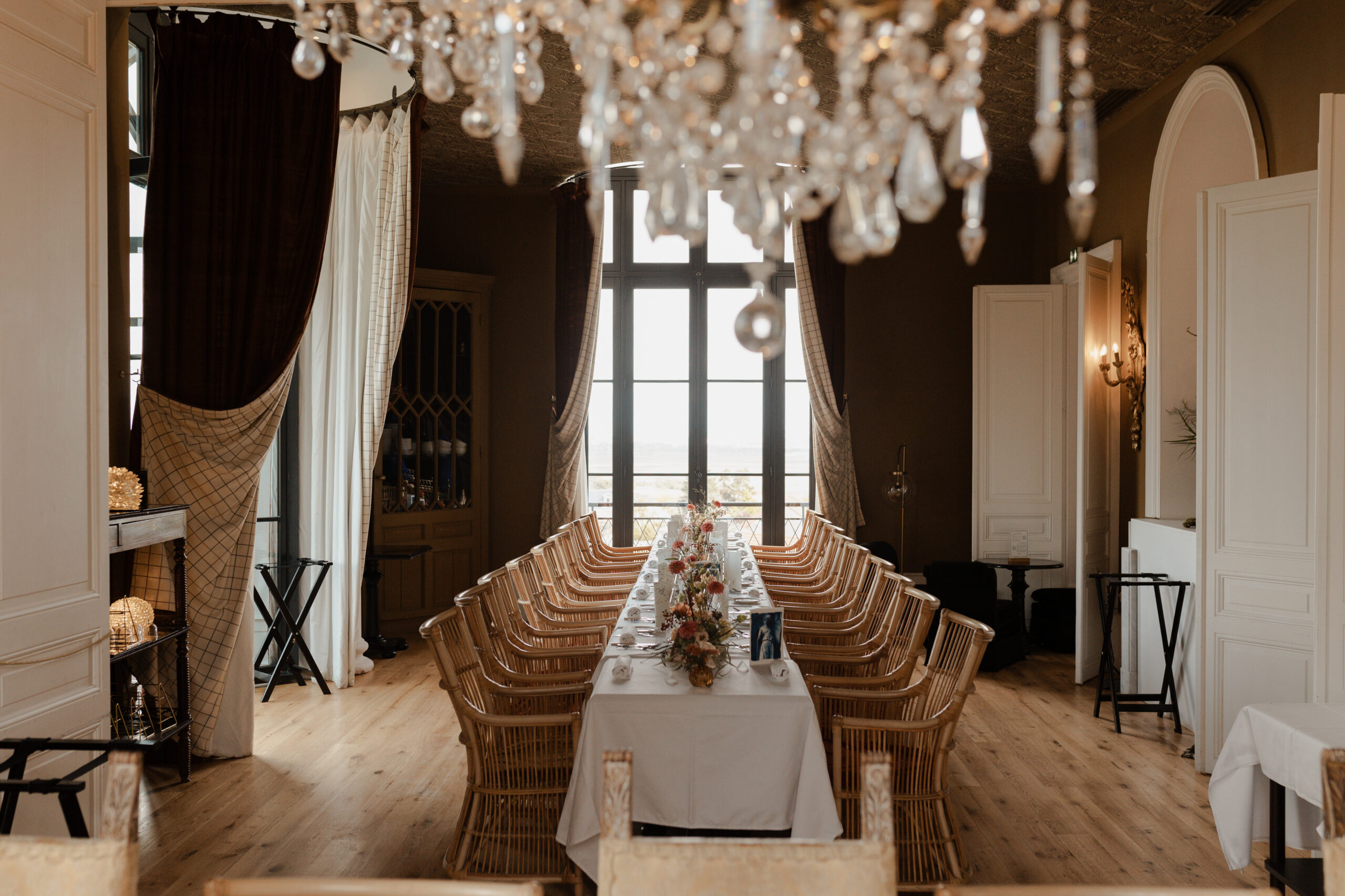Table de banquet dressée dans la salle de restaurant luxueuse du Château de Sacy. Un lustre en cristal surplombe la table décorée avec élégance pour une réception de mariage.