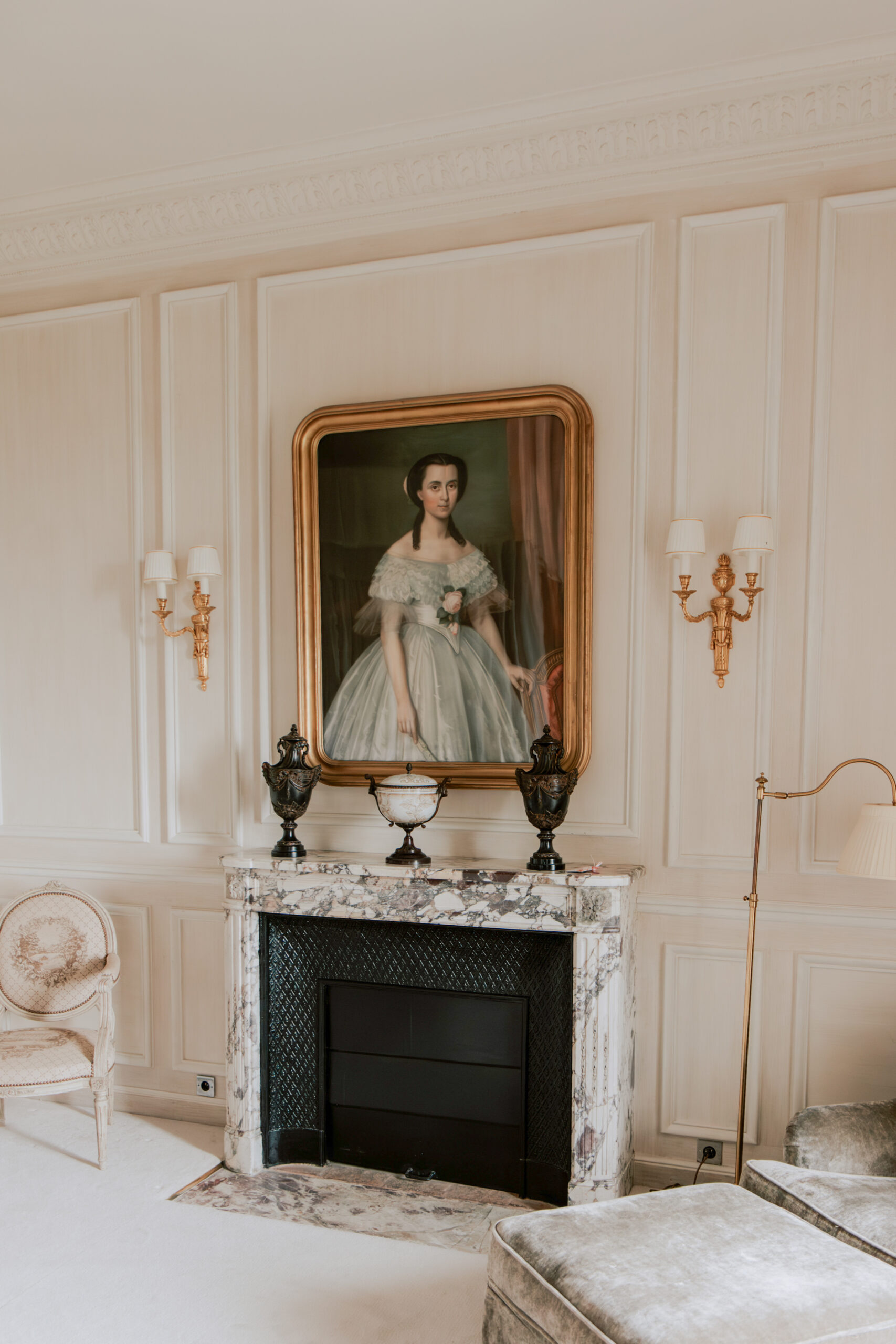 Photographie de détail en couleur d'une chambre luxueuse au Domaine des Crayères à Reims, en Champagne. Gros plan sur une magnifique cheminée ancienne en pierre, surmontée d'un grand portrait classique. Ambiance élégante et historique pour les préparatifs d'un mariage de prestige près de Reims.