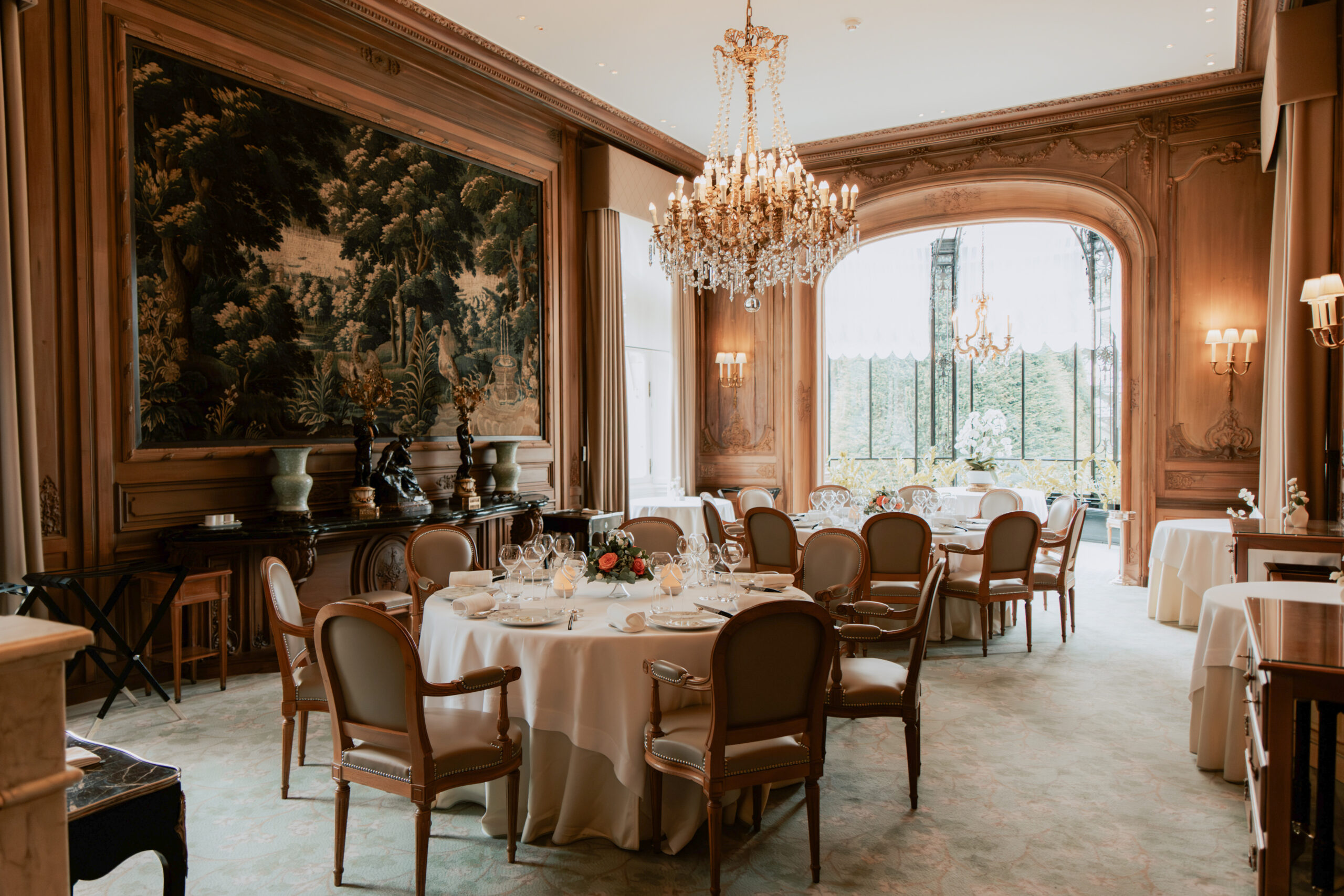 Vue d'ensemble de la salle de réception du Domaine des Crayères à Reims. Décoration de mariage luxueuse avec lustres en cristal, murs boisés et moulures historiques.
