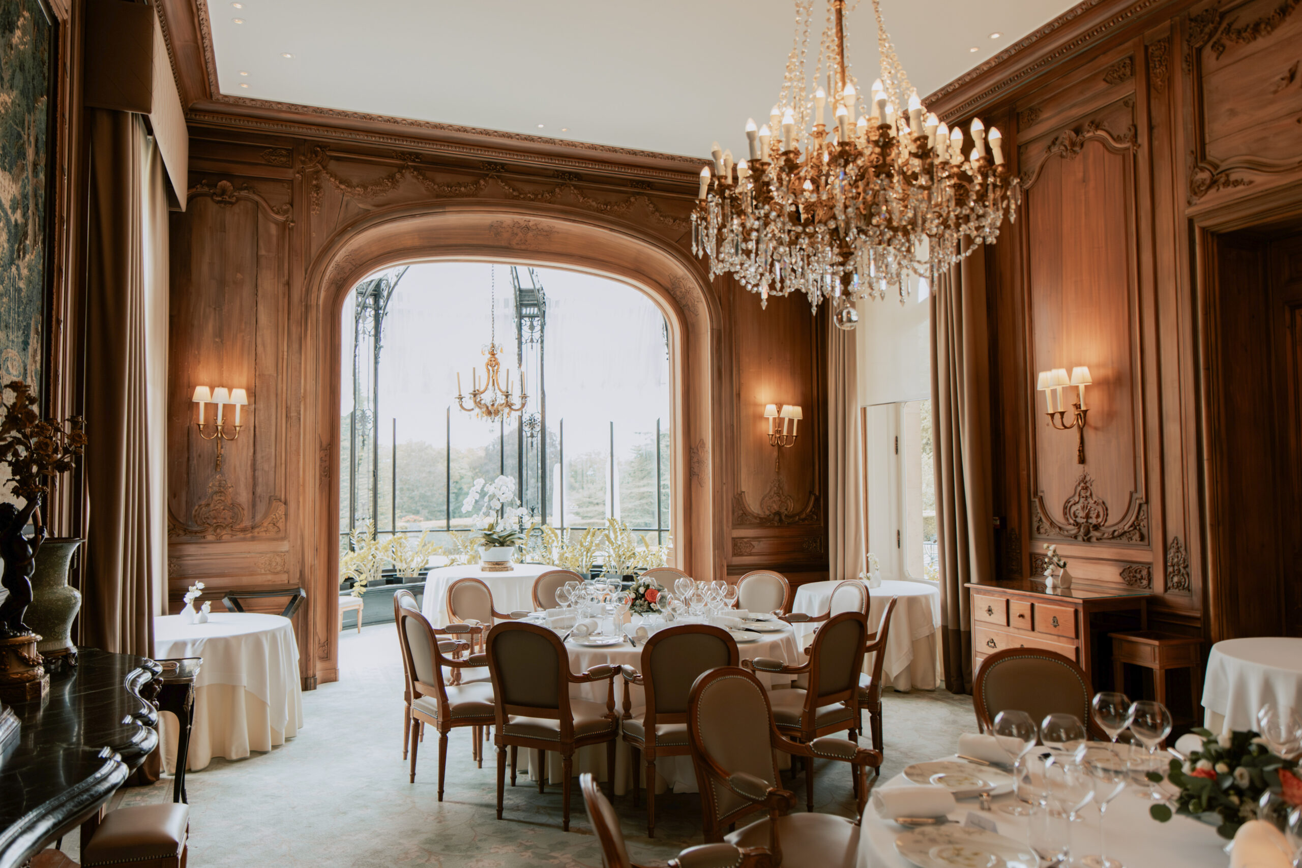 Salle de mariage prête pour le dîner au Domaine des Crayères, Reims. Les tables sont dressées sous les boiseries élégantes du château en Champagne.