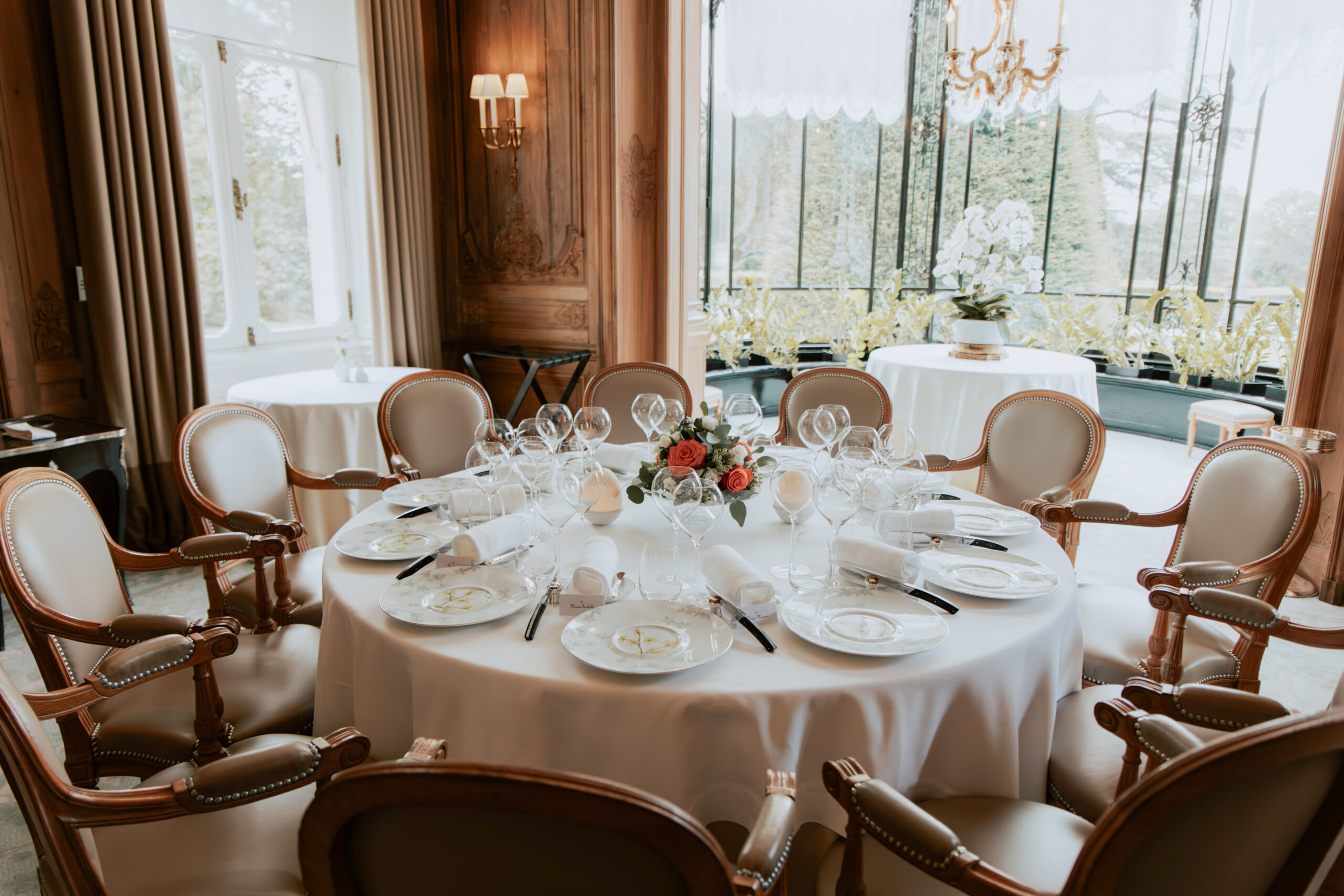 Gros plan sur une décoration de table de mariage au Domaine des Crayères. Vaisselle fine, verres en cristal et papeterie élégante sur nappe blanche.