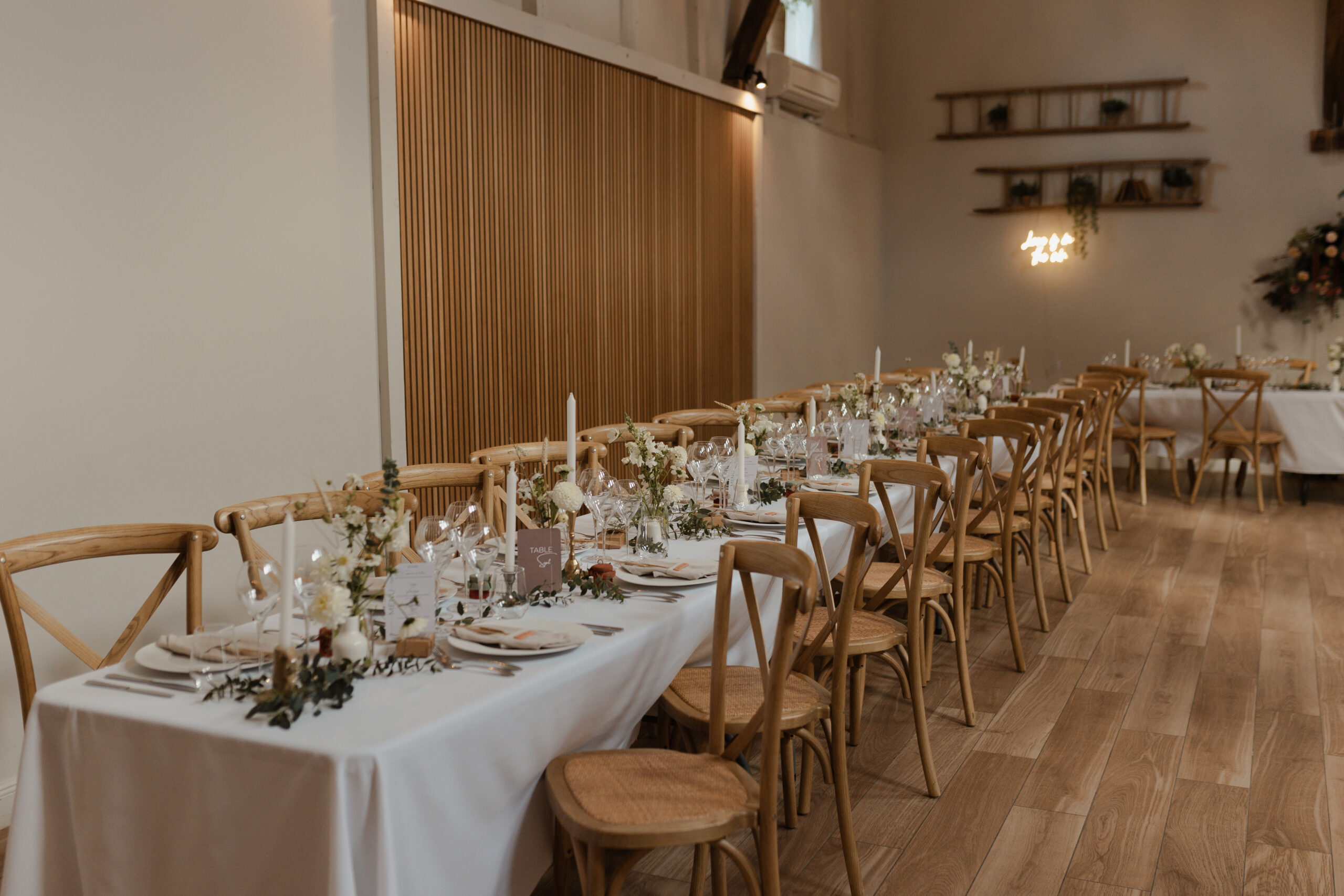 Vue d'ensemble d'une longue table de banquet dressée pour un mariage au Domaine de La Closeraie. La décoration riche et élégante comprend de nombreuses bougies, des compositions florales généreuses et une vaisselle raffinée en Champagne.