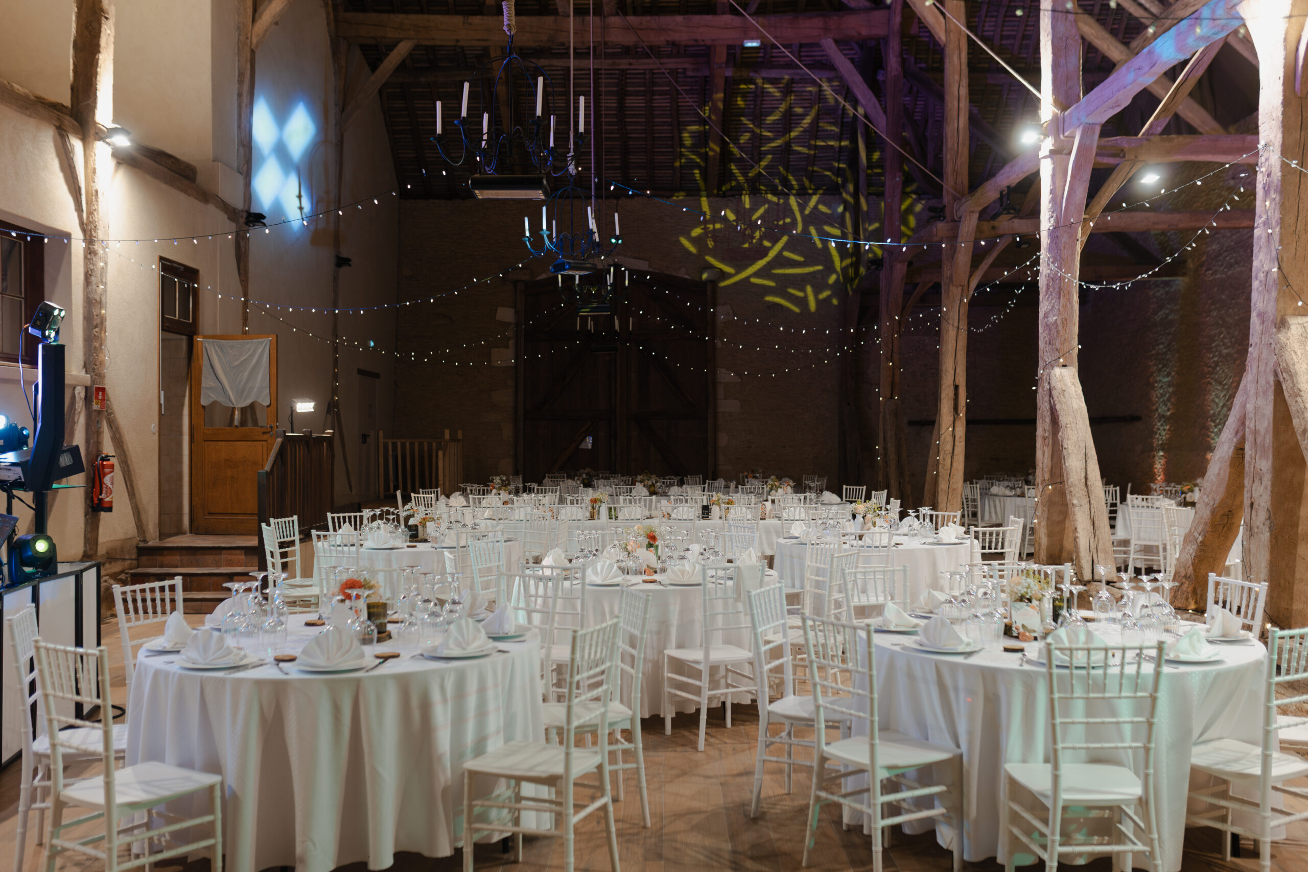 Grange du Château de Vaux décorée avec des guirlandes guinguettes suspendues au-dessus des tables.