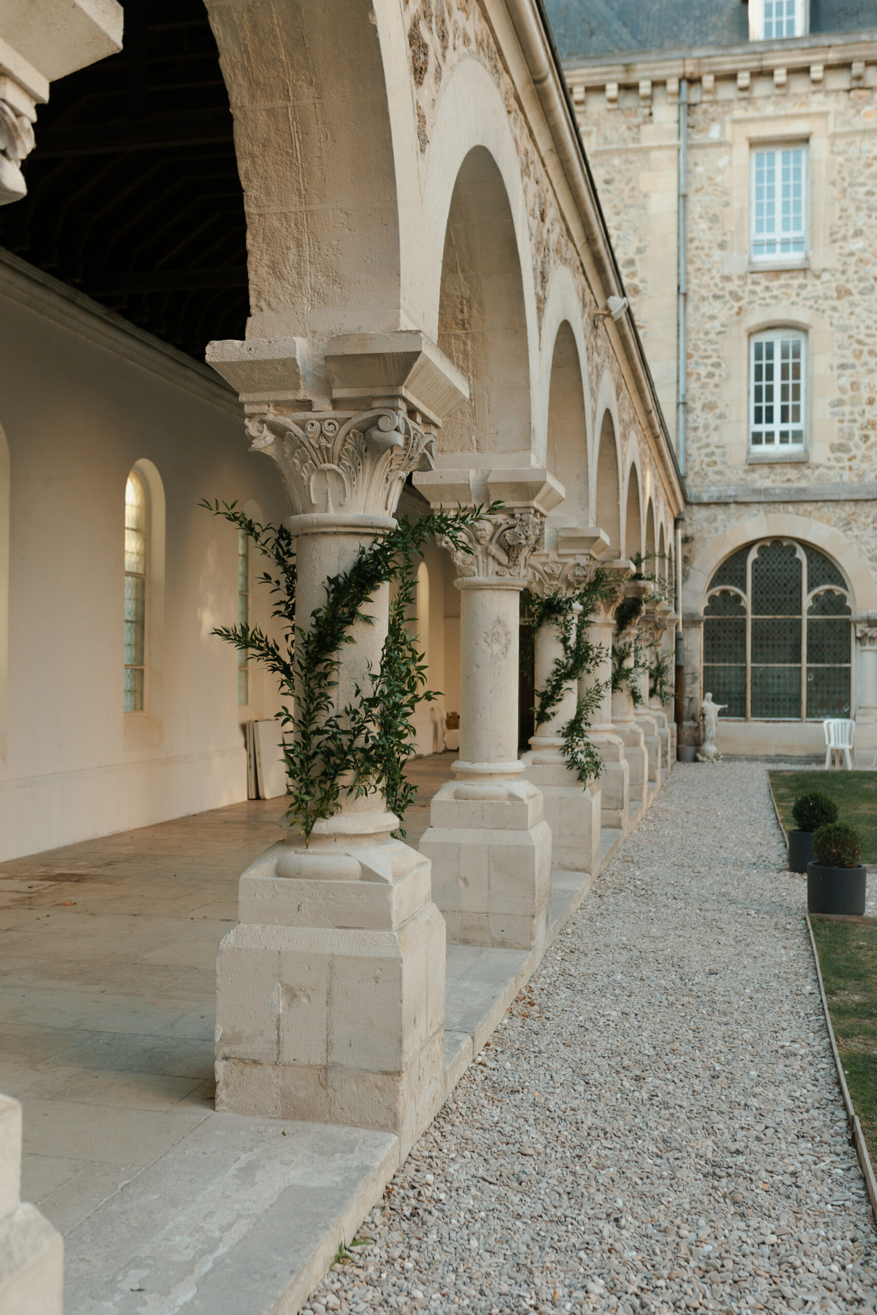 Colonnes du cloître décorées de feuillage pour une cérémonie au Prieuré de Binson, domaine mariage Reims Champagne.