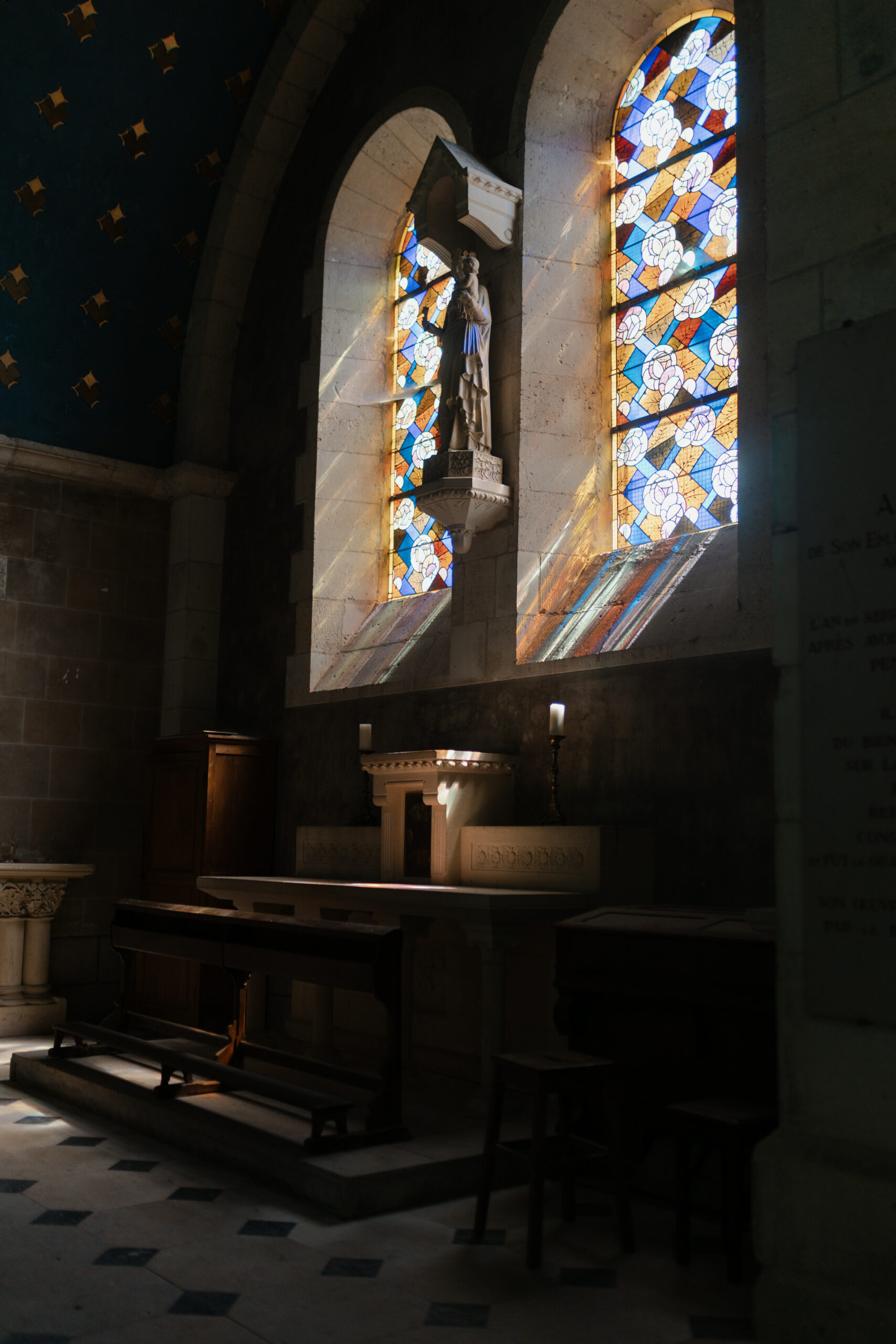 Autel de l'église avec lumière du soleil traversant le vitrail, créant des reflets colorés et lumineux.