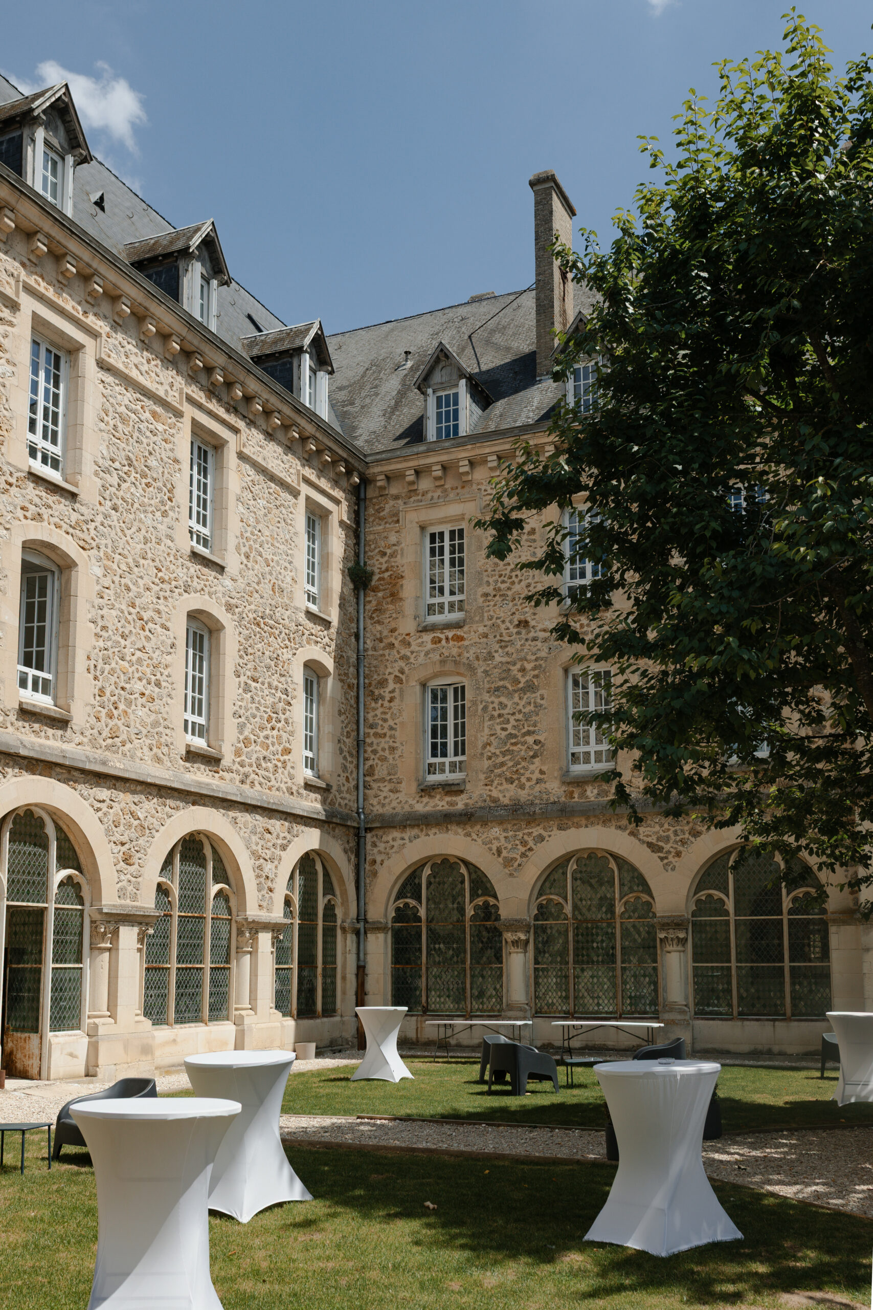 Vue extérieure du cloître du Prieuré de Binson sous un soleil d'été. Architecture de pierre de ce domaine de mariage prestigieux.
