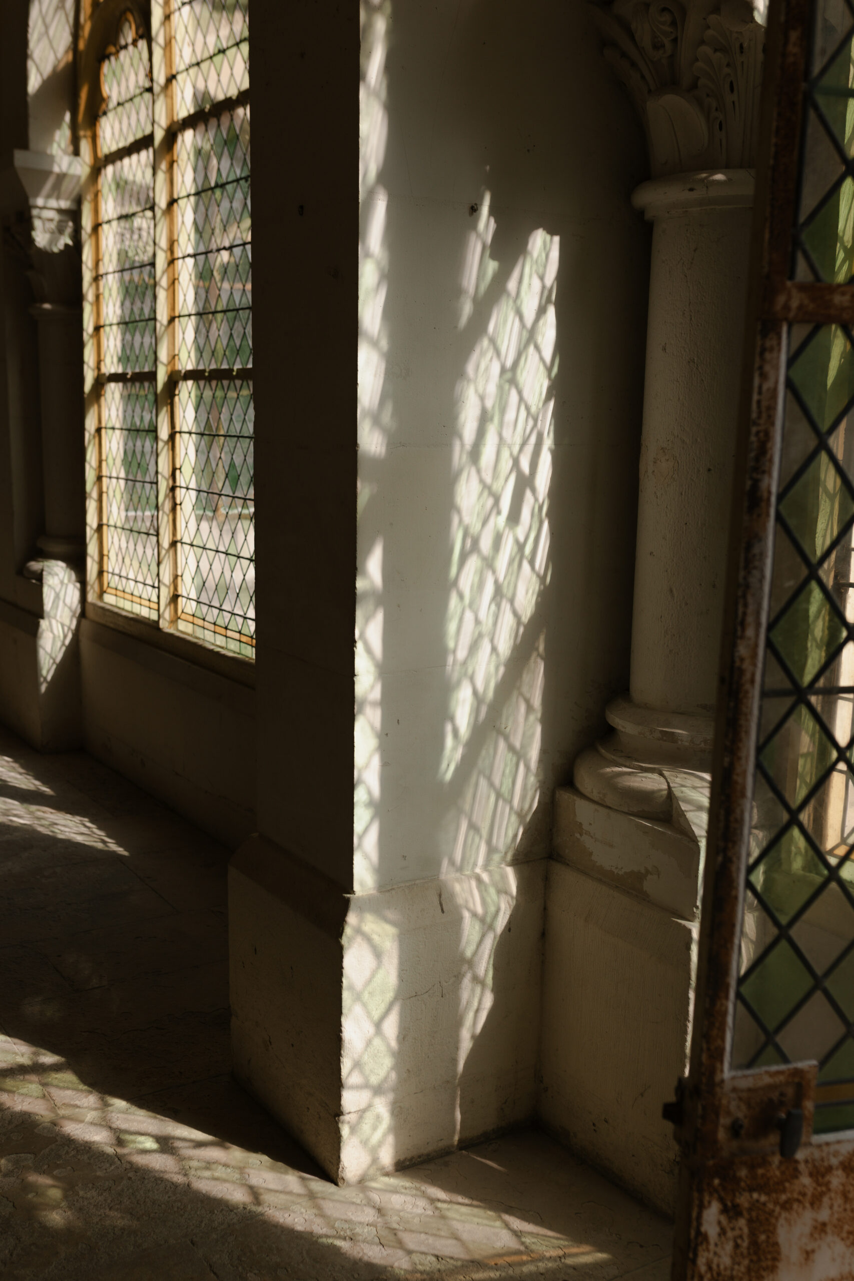 Ombres et reflets colorés d'un vitrail sur un mur du couloir au Prieuré de Binson, domaine mariage Reims.