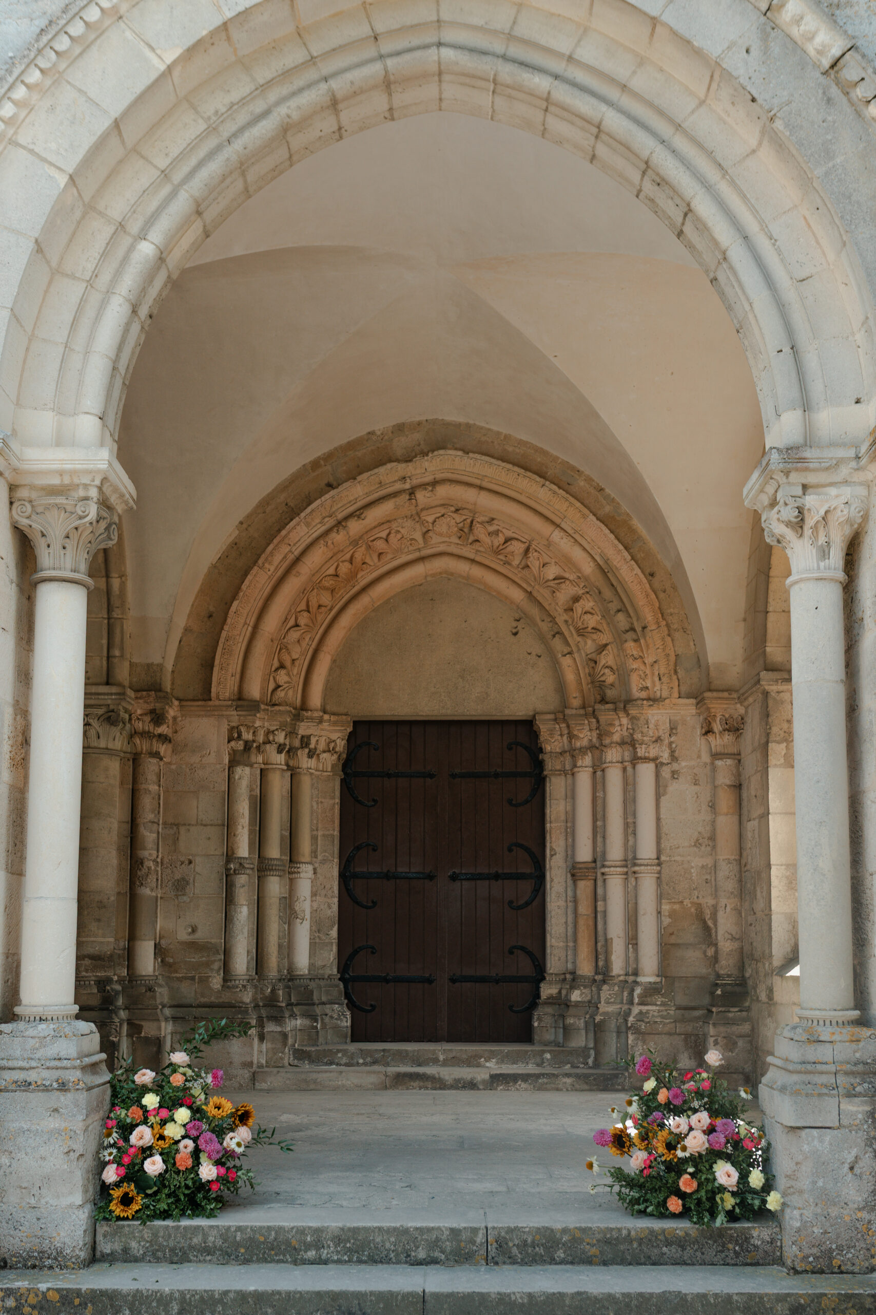 Porche de l'église du Prieuré de Binson avec compositions florales de Les Babineries de Marie aux pieds des colonnes.