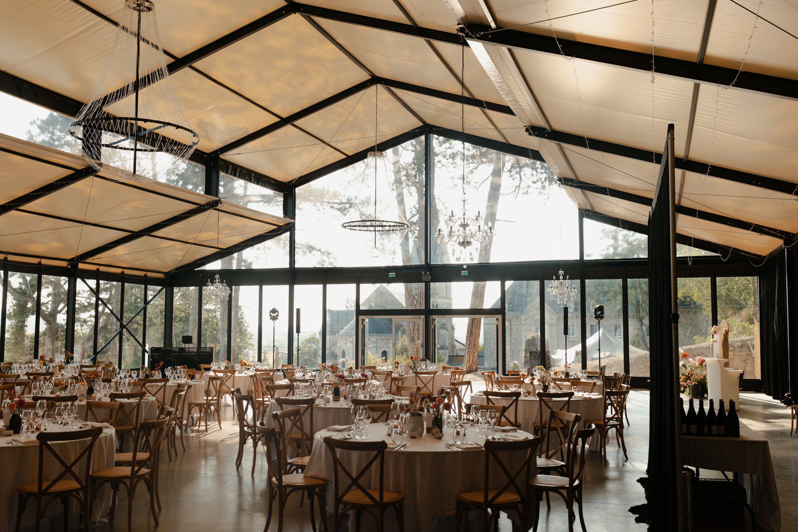 Vue de l'orangerie côté entrée avec grandes fenêtres vitrées et perspective sur le bâtiment historique du Prieuré.