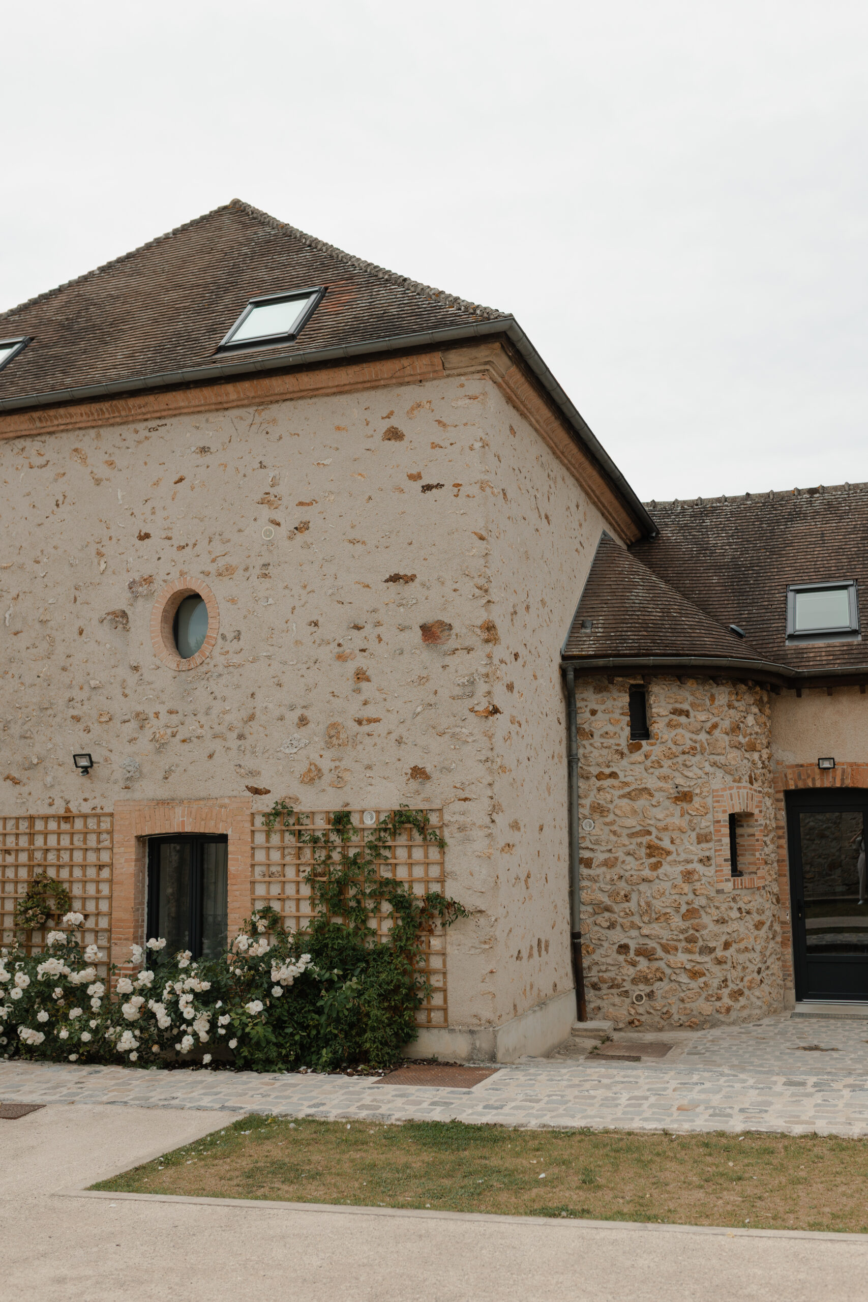 Photo extérieure de la grange du domaine La Farm avec ses fleurs blanches grimpantes, domaine mariage Reims Champagne.