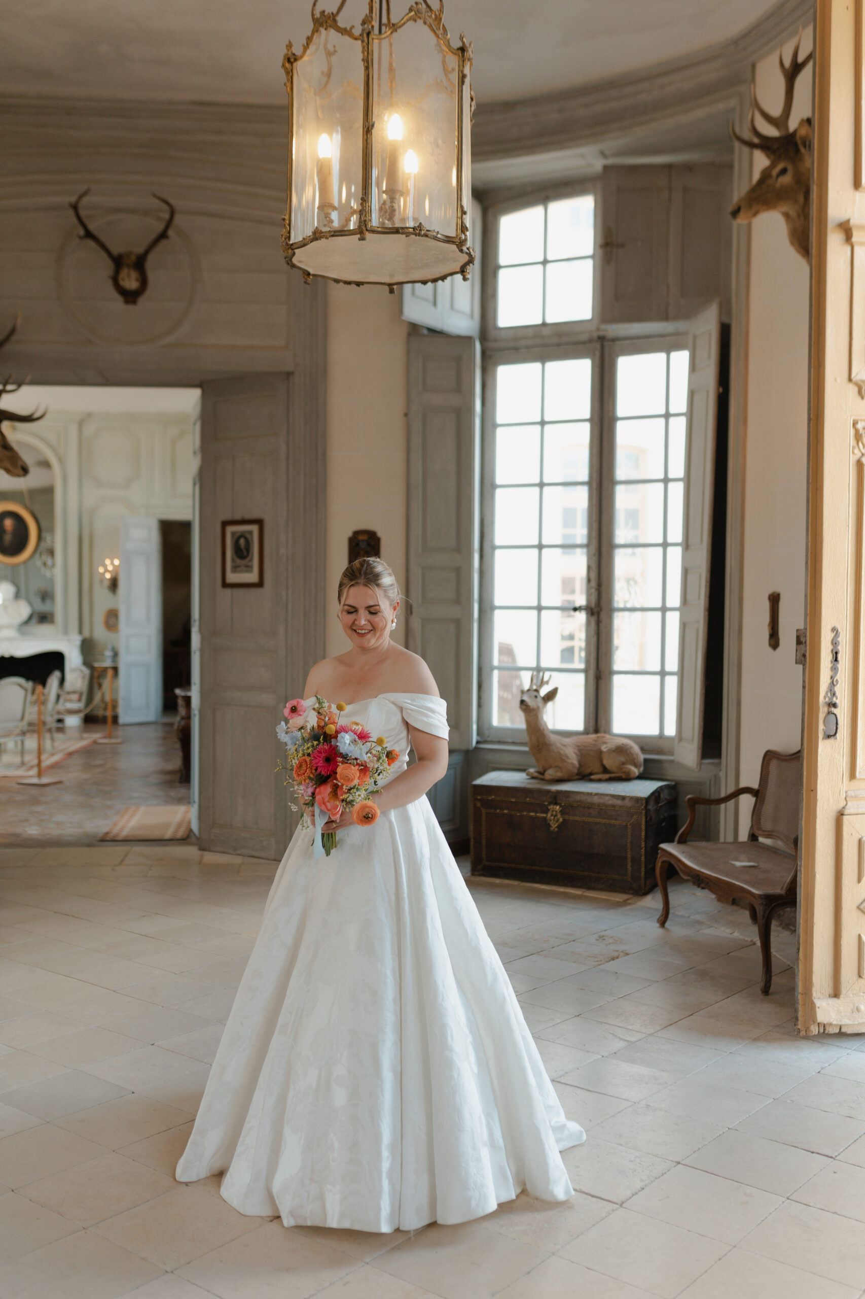 Portrait en pied de la mariée dans le hall majestueux du Château de Vaux, domaine mariage Reims.