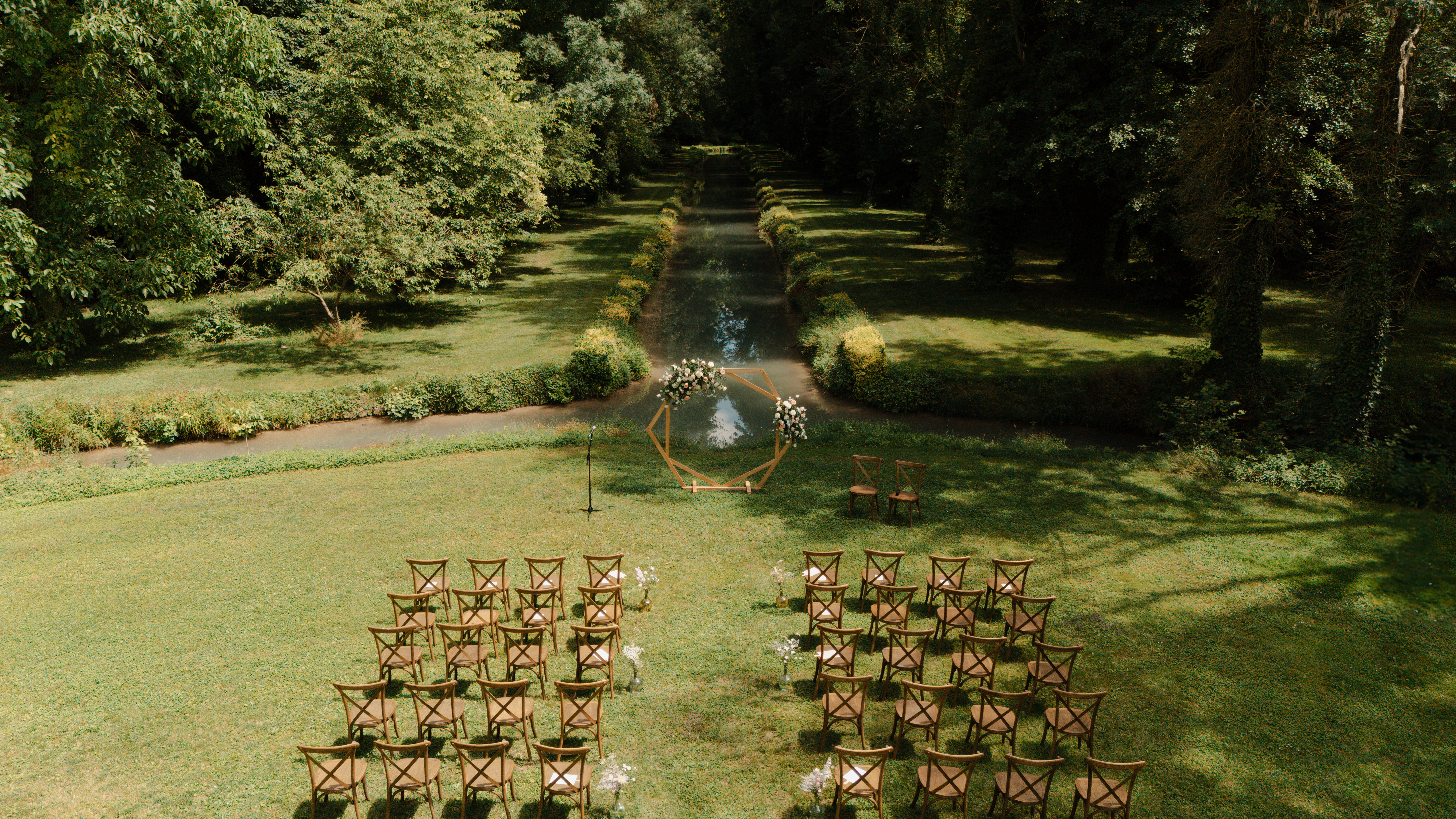 Vue drone d'une cérémonie laïque installée devant la rivière au Domaine de Vaugency, dans un écrin de verdure.