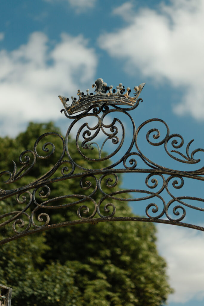 Gros plan sur la couronne en fer forgé située en haut de la grille d'entrée du Domaine de Vaugency.