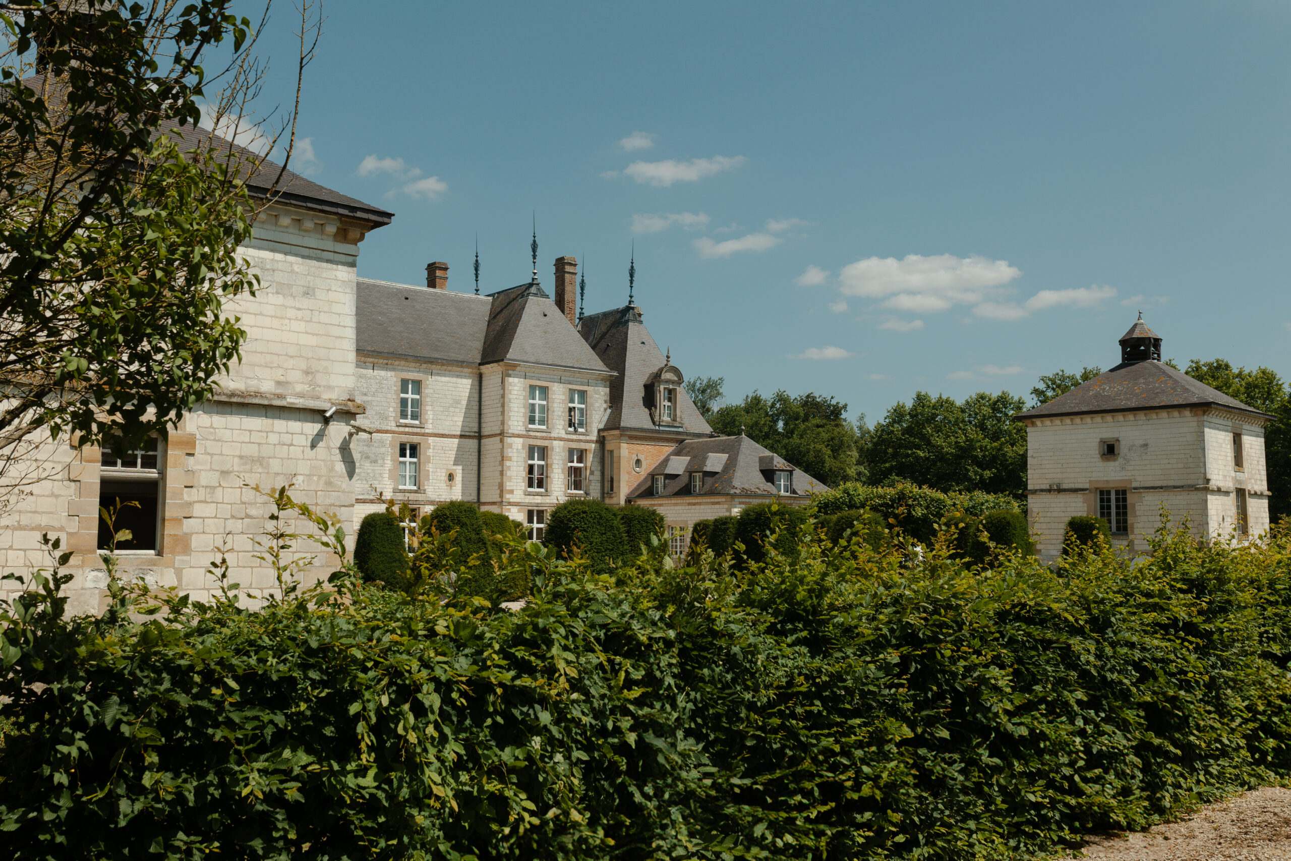 Vue de côté du Château de Vitry-la-Ville avec des buis taillés au premier plan encadrant l'architecture.