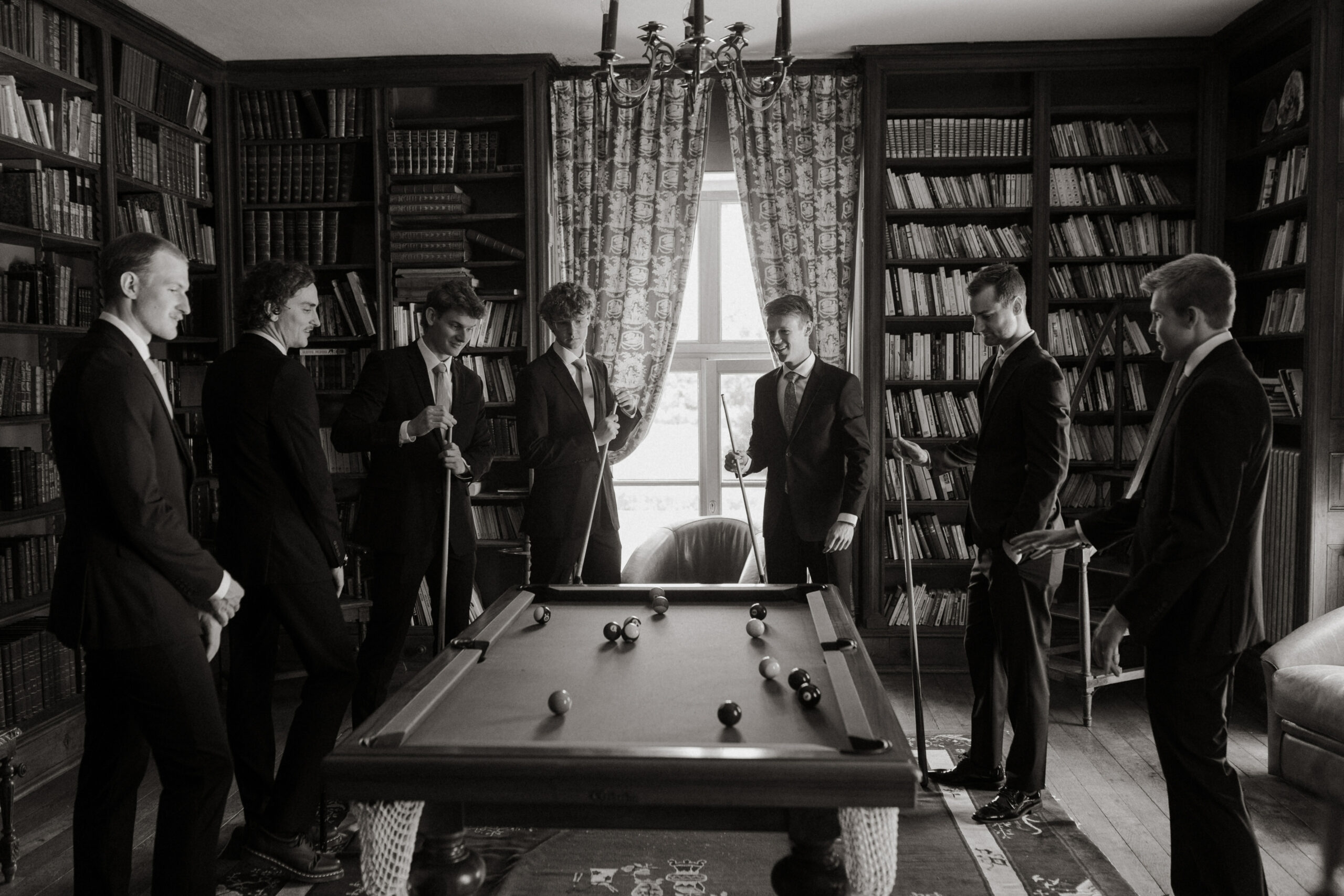 Photo en noir et blanc du marié jouant au billard avec ses garçons d'honneur au Château de Vitry-la-Ville.