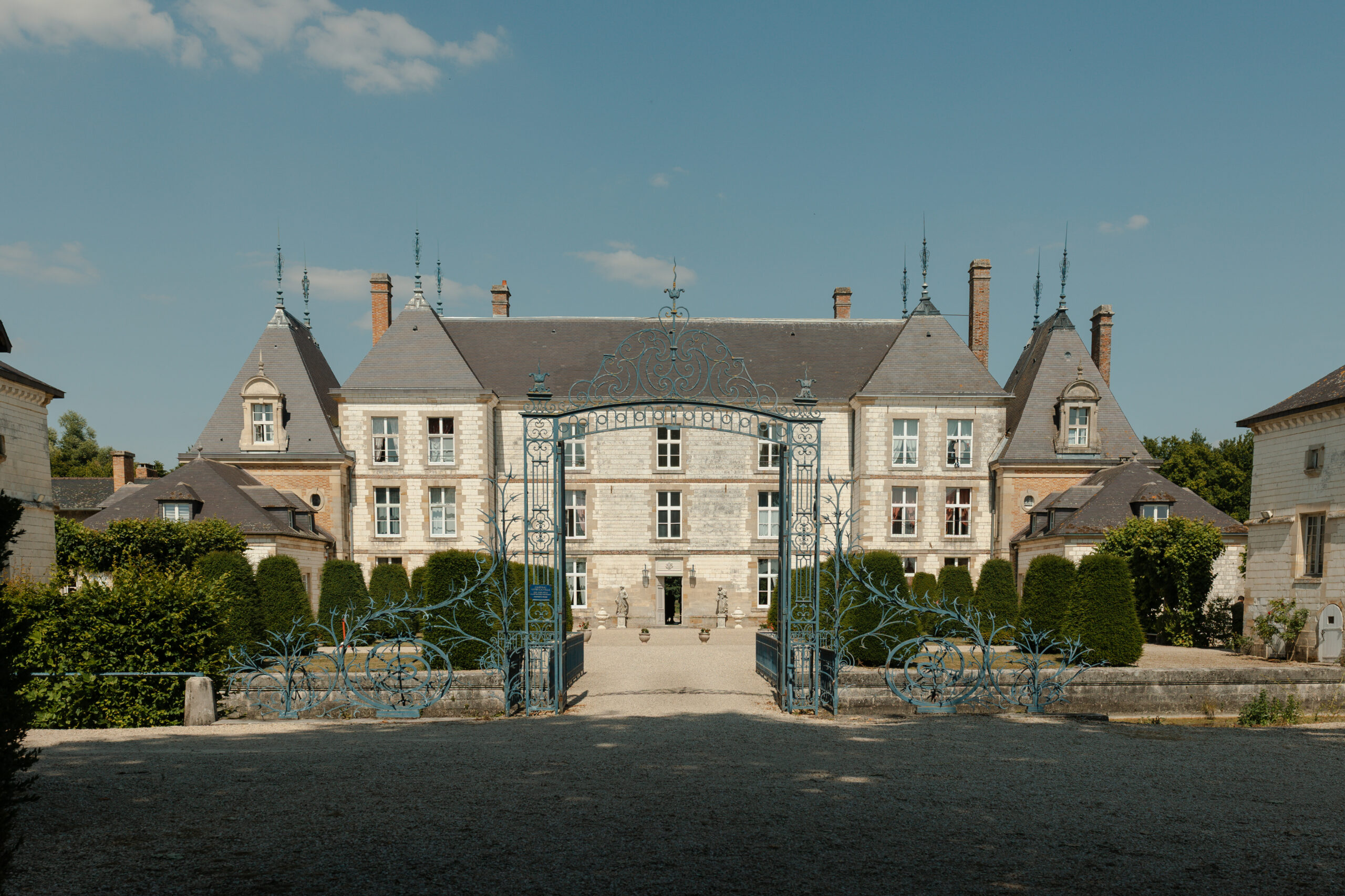 Vue avant du Château de Vitry-la-Ville montrant la grille, les douves et les arbres taillés à la française.