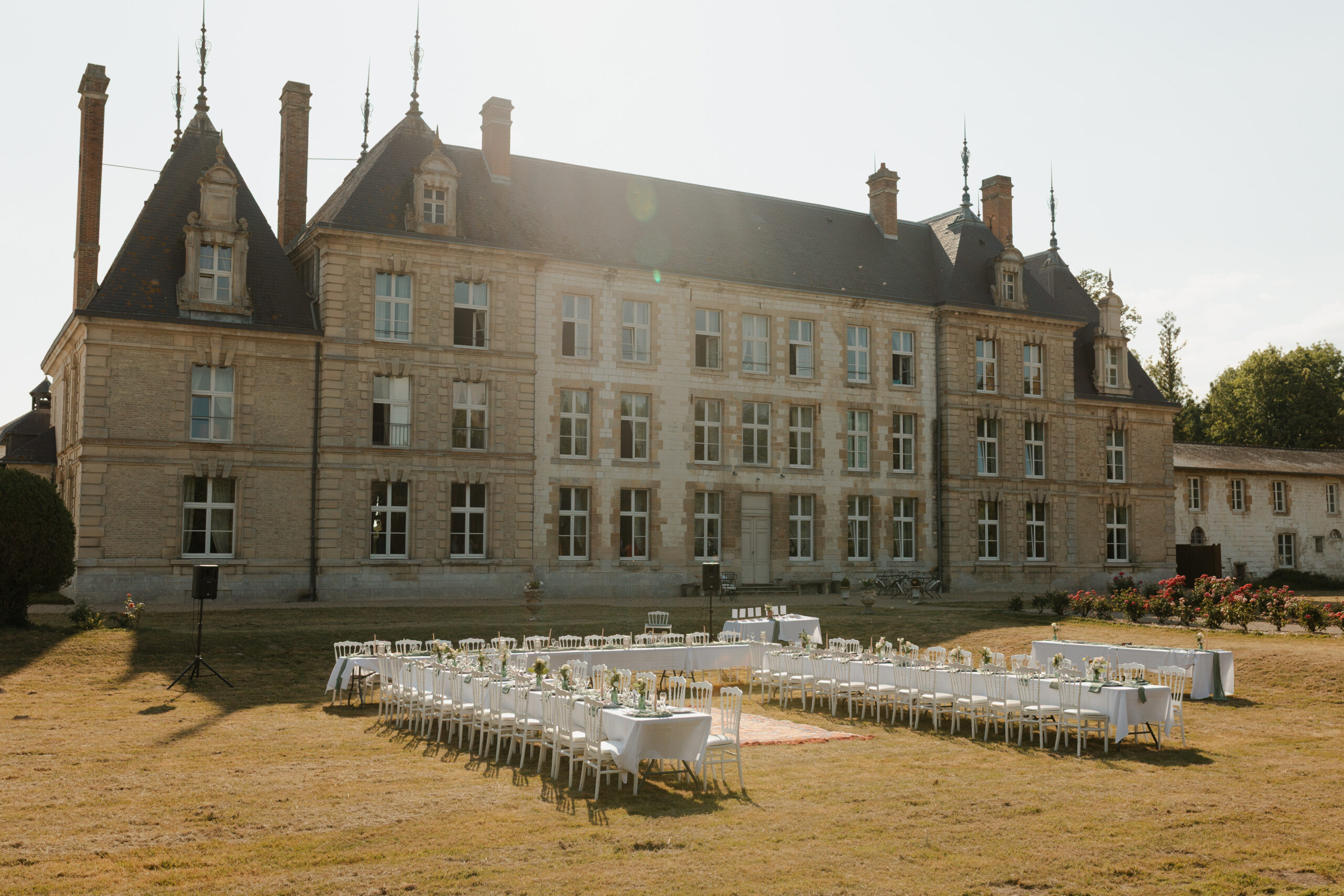 Réception de mariage dans le parc avec le Château de Vitry-la-Ville en arrière-plan des tables dressées.